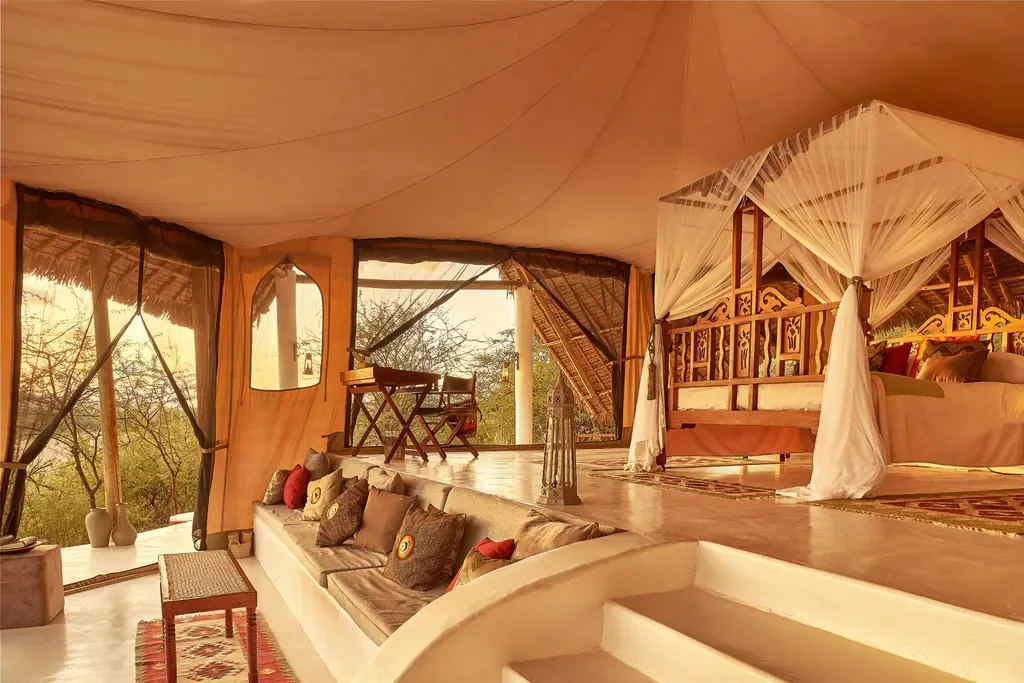 Spacious Sasaab suite interior with carved bed and lounge, open-sided tent overlooking Samburu, Kenya