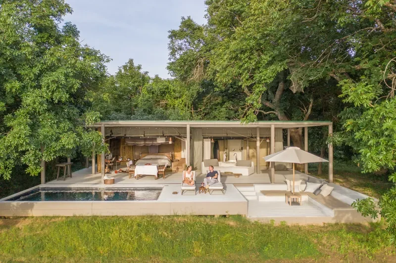 Couple on pool terrace at Time + Tide Chinzombo at sunset, Luangwa River views, luxury safari, South Luangwa, Zambia
