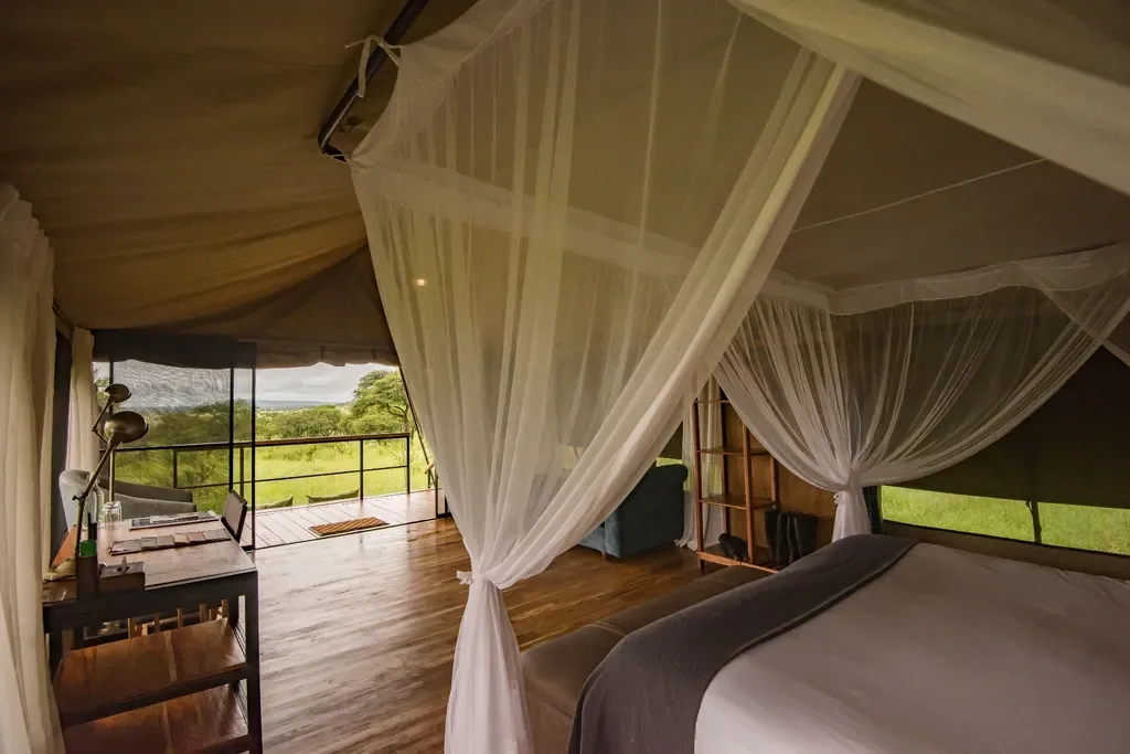 Dunia Camp safari tent interior opening to deck, netted bed and writing desk, Serengeti