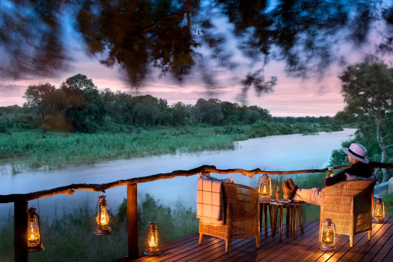 Guest deck at Lion Sands Tinga Lodge overlooking the Sabie River at dusk, lantern-lit safari setting