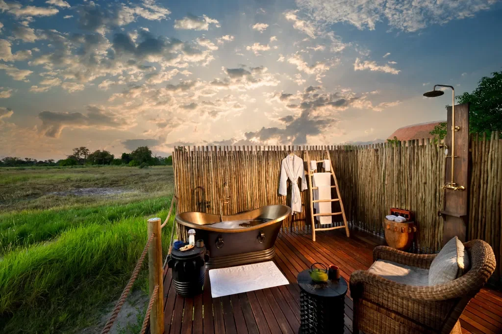 Outdoor copper bath and shower on deck at Atzaro Okavango Camp with wide Delta views, Botswana
