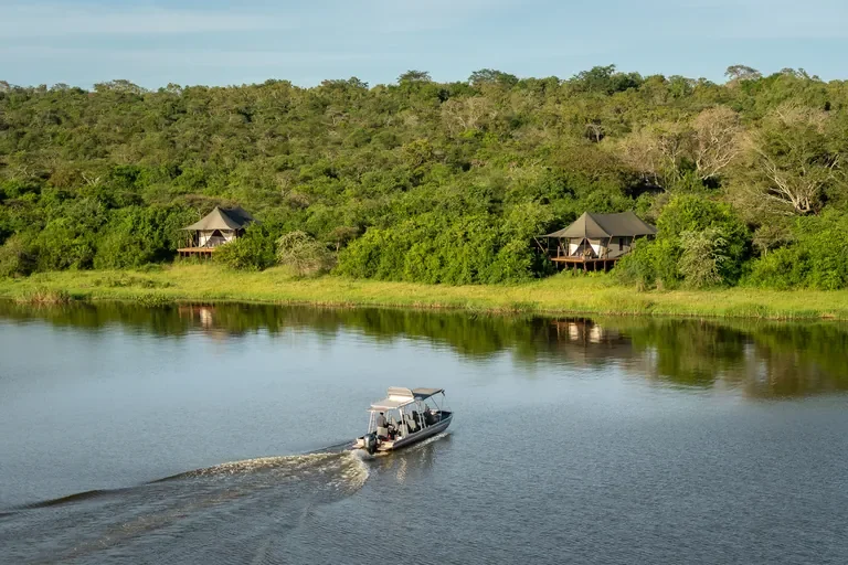 Boat safari on Lake Rwanyakazinga passing Magashi Camp tents, Akagera Rwanda