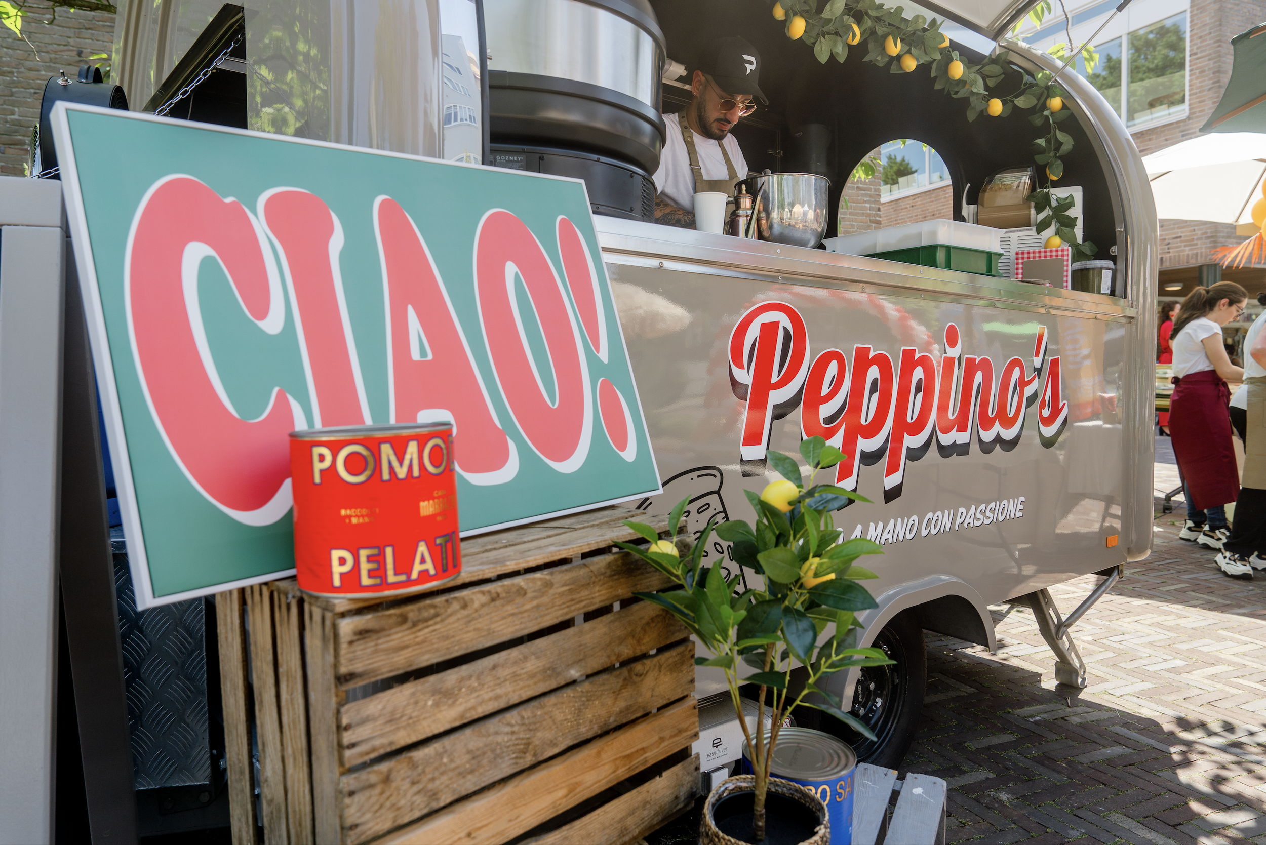A food truck named Peppino's selling Sicilian-style pizza at an outdoor event. The truck has a large sign with the word 'CIAO' and a small potted lemon tree in front.