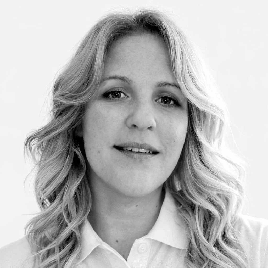 Black and white portrait of a woman with shoulder-length hair, smiling at the camera, wearing a collared shirt.