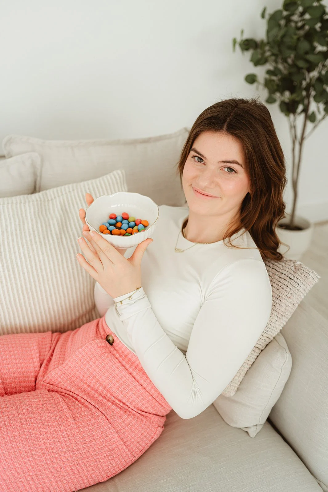 Een vrouw zit op een bank en houdt een kom met kleurrijke kleine balletjes.