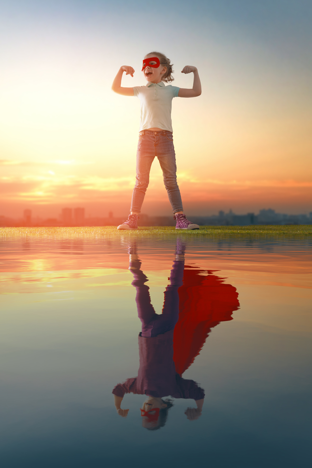 Une fillette portant un masque rouge, se tenant en position de force avec les bras fléchis, devant un coucher de soleil, avec sa reflection dans l'eau.