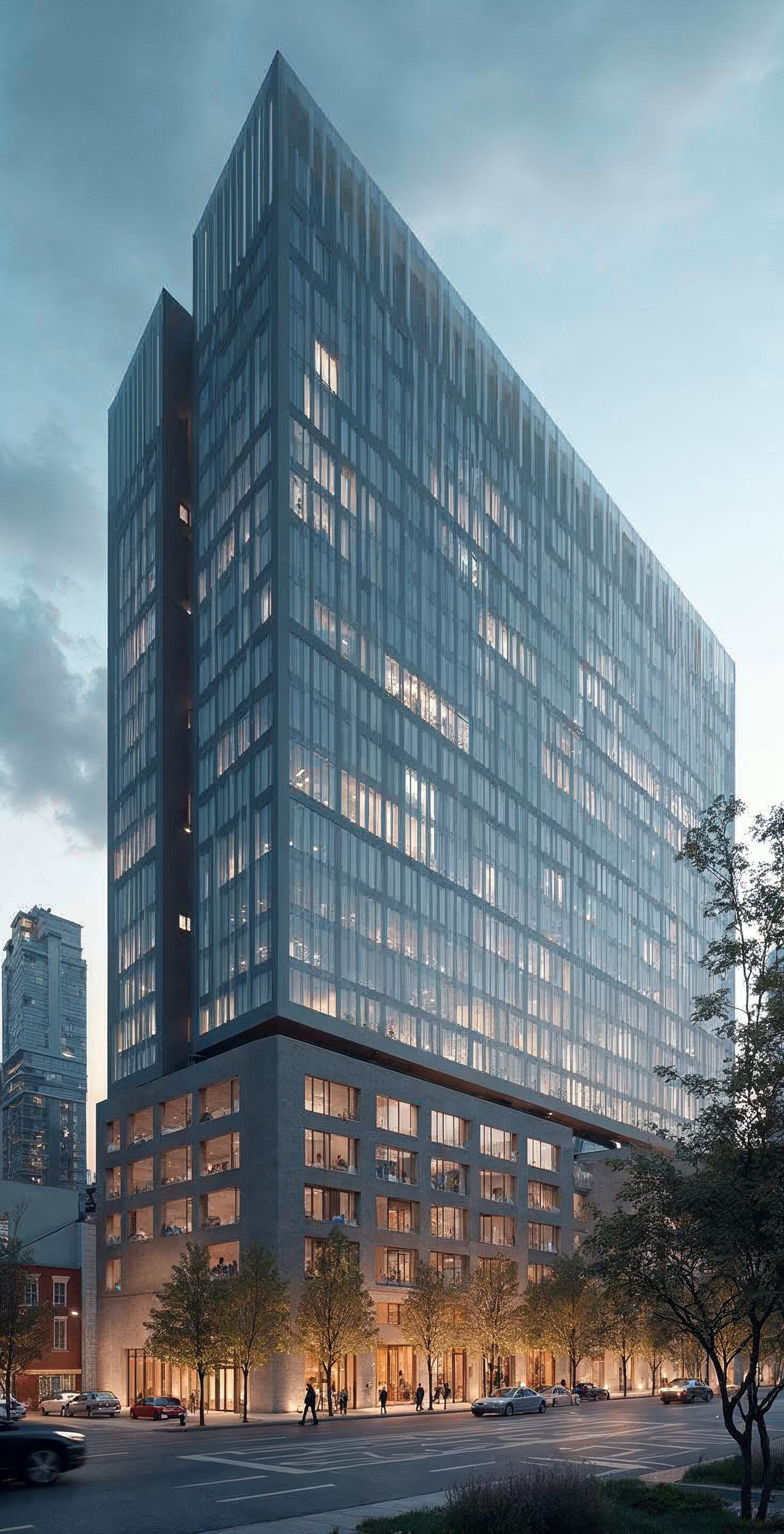 A modern, glass-covered high-rise building with a distinctive two-story base, located in an urban area with trees, cars, and pedestrians at street level during dusk.