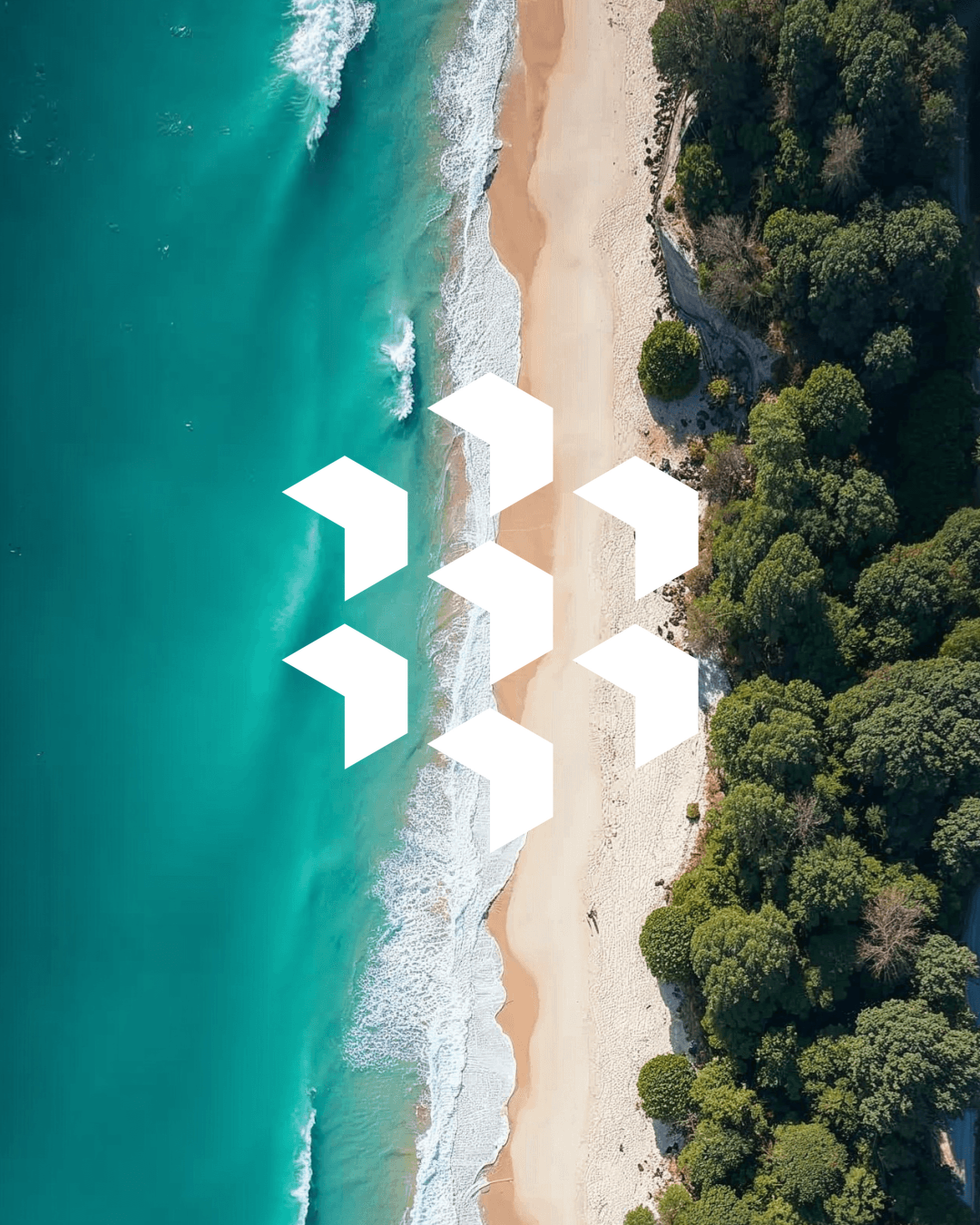 Aerial view of a sandy beach with turquoise ocean waves and a forested area on the right side.