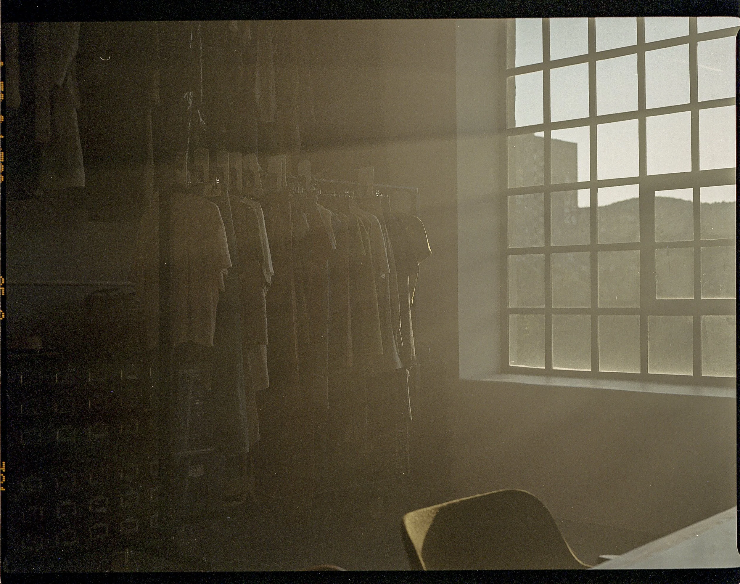 Clothes hanging on racks near a large window letting in sunlight.
