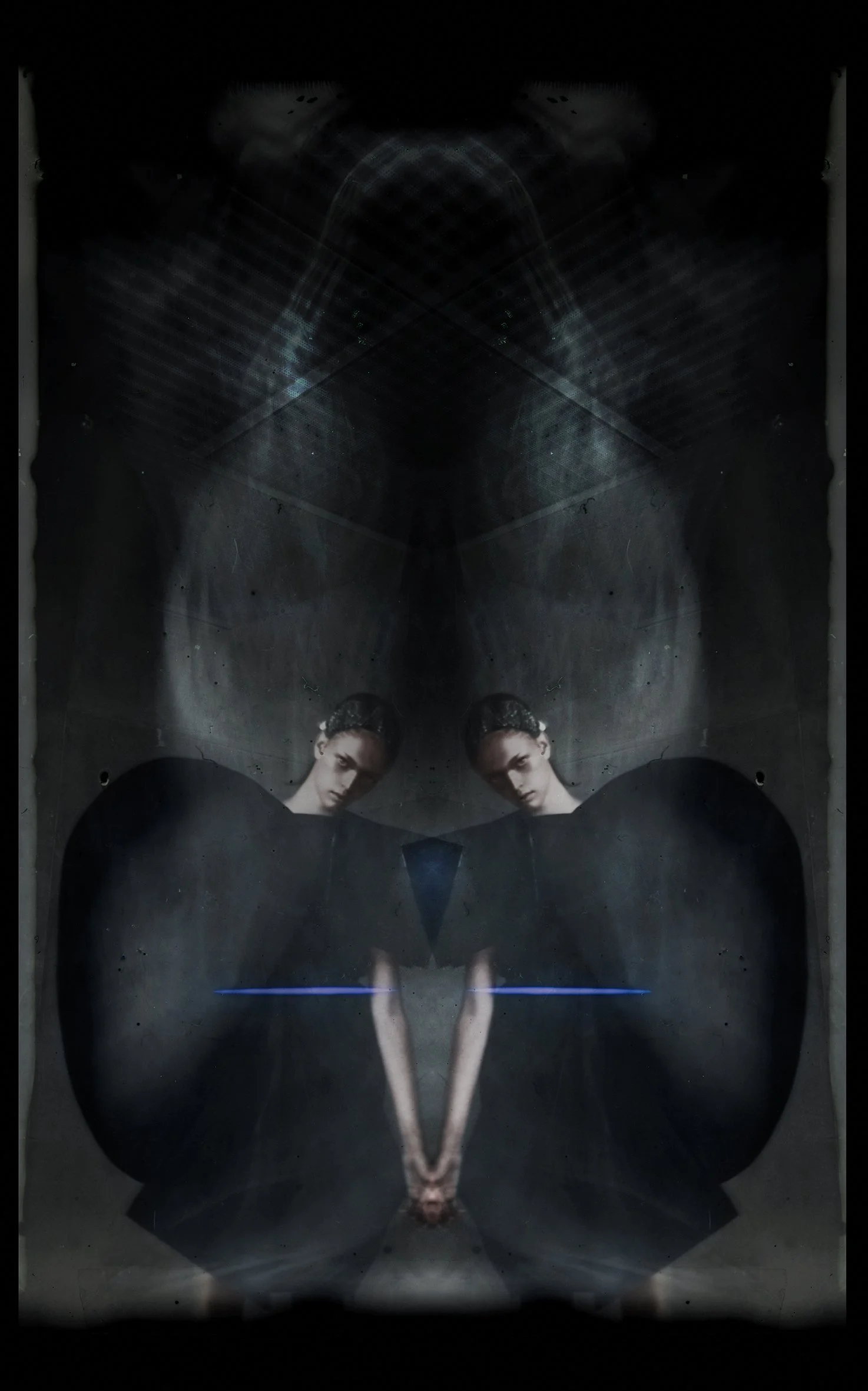 A mirrored image of a woman sitting with her arms resting on her knees, in a dimly lit, industrial-looking space with a dark background. She is wearing a black outfit and has her hair styled back.