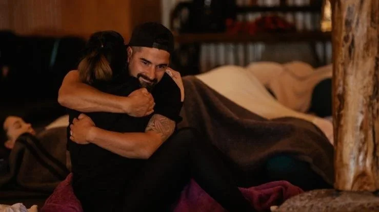 A man and woman embracing and hugging each other warmly in a cozy indoor setting.