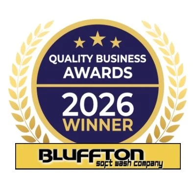 Award badge with gold laurel wreath, navy blue circle, three gold stars, and text indicating 'Quality Business Awards 2026 Winner' for Bluffton Soft Wash Company.
