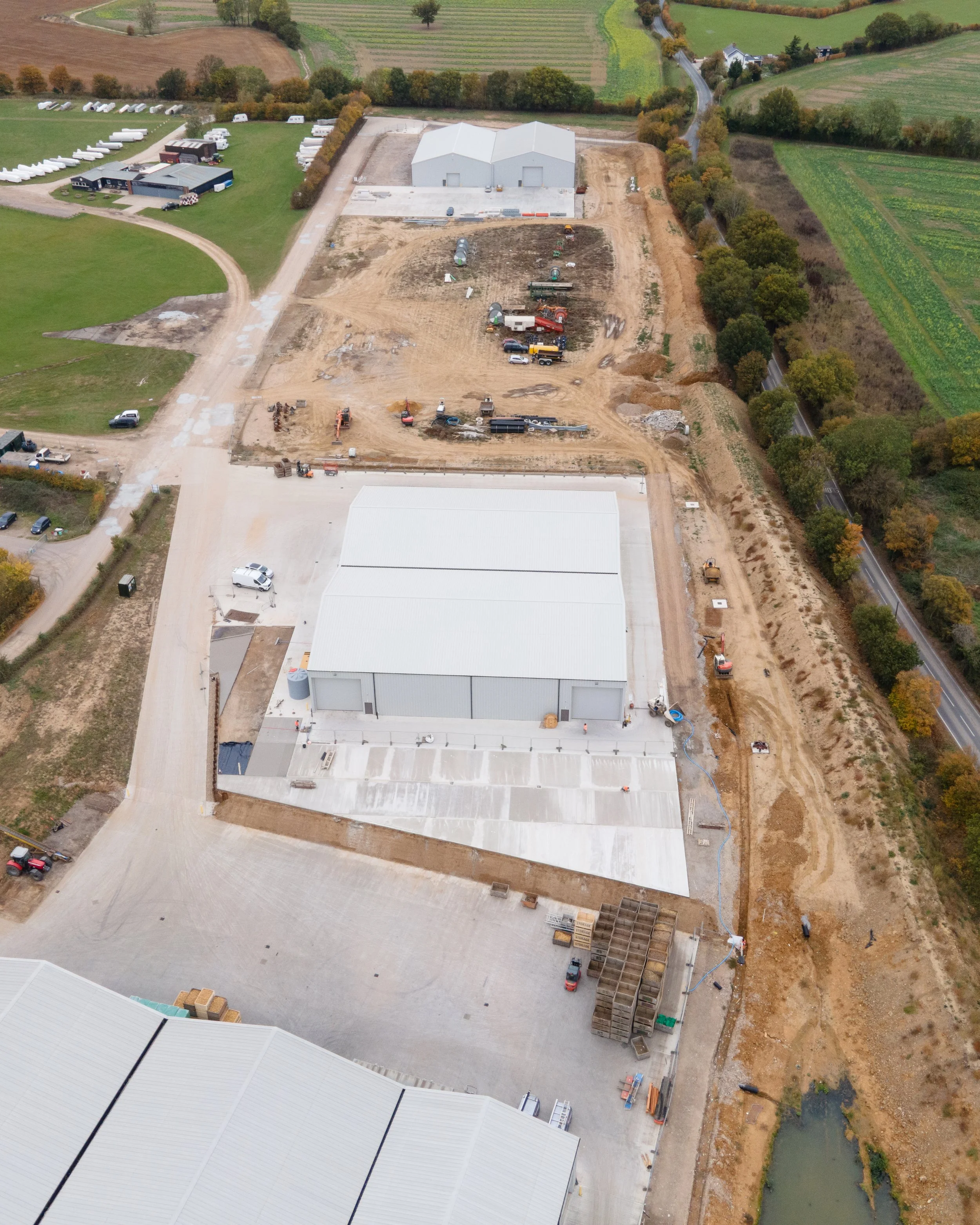 Two Anglia Concrete Finishing Ltd construction workers standing next to a concrete mixer truck at a construction site. ACF 
