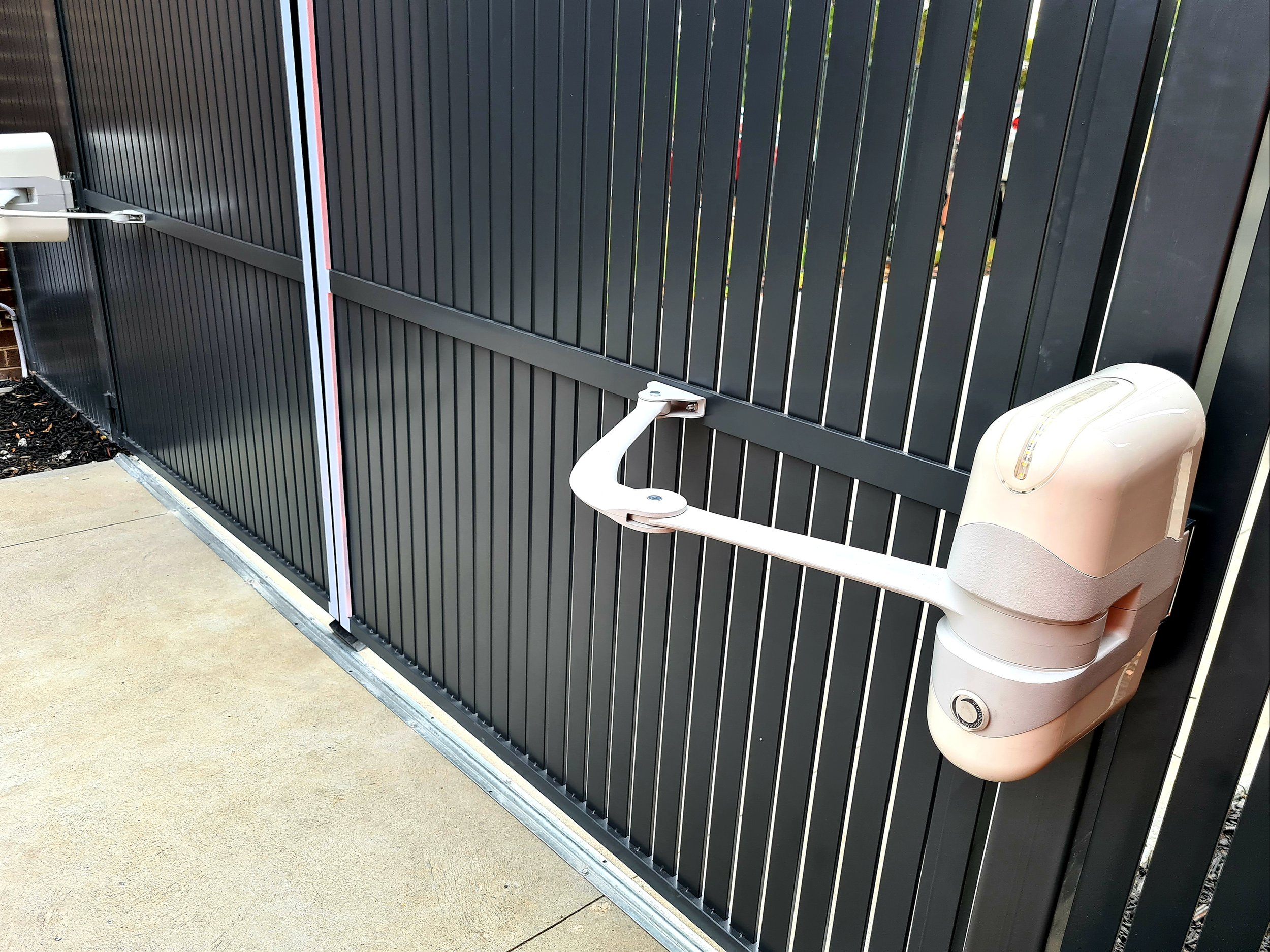 Automated gate with a horizontal bar and a security lock, installed on a concrete driveway.
