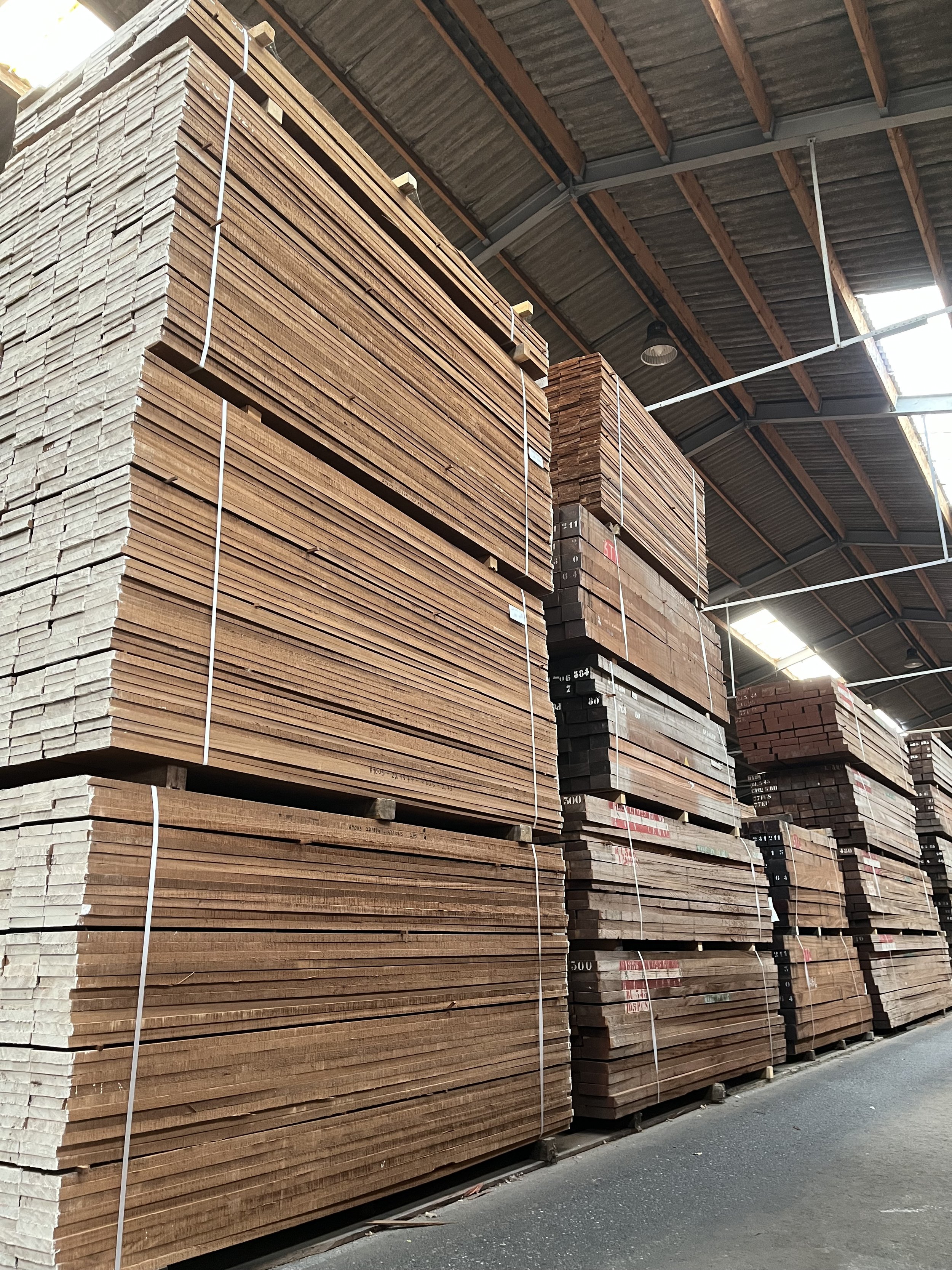 gestapelde thermo ayous planken en balken in een bouwmarkt of opslagplaats.