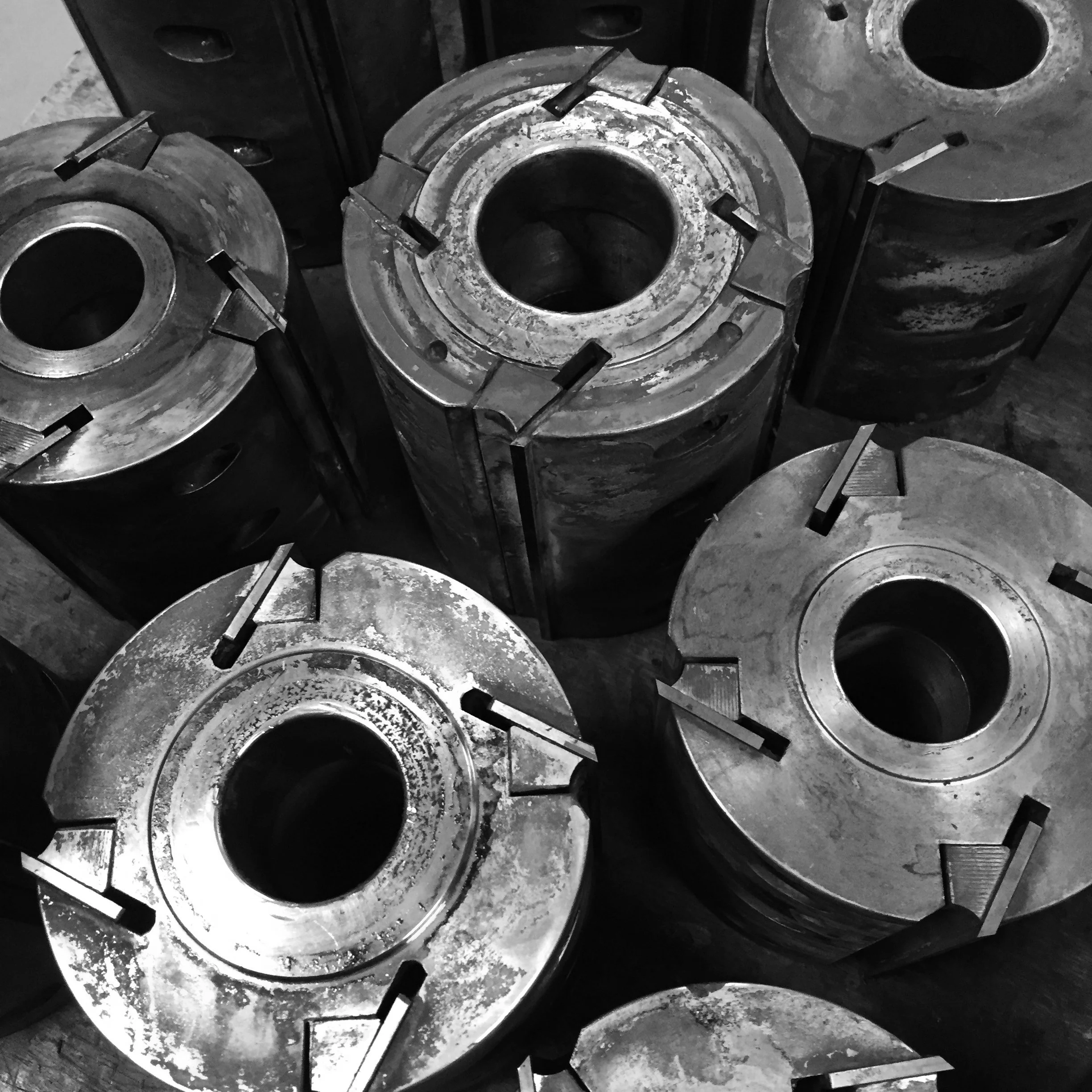 Zes grote metalen mallen met centrale opening, gestapeld en uitgelijnd in een werkplaats.