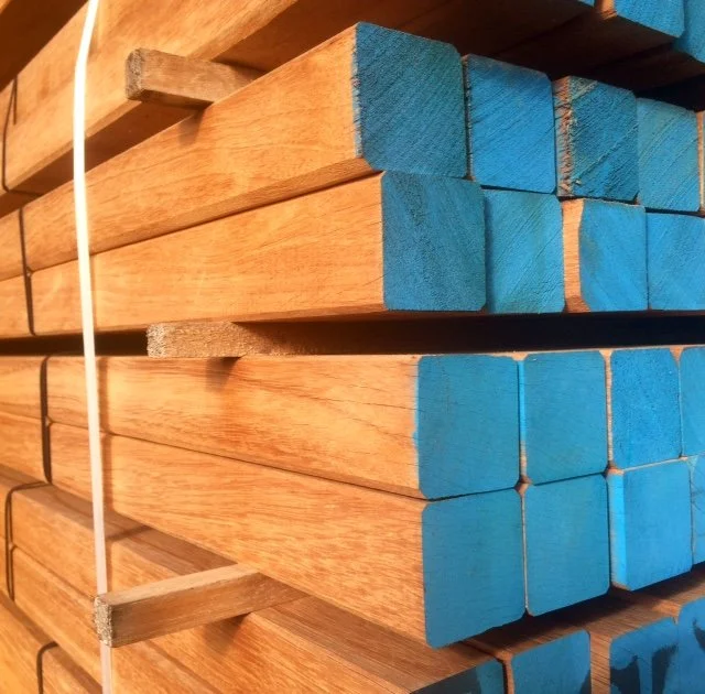 Houten planken met blauwe koppen gestapeld op een plank, vastgemaakt met wit touw.