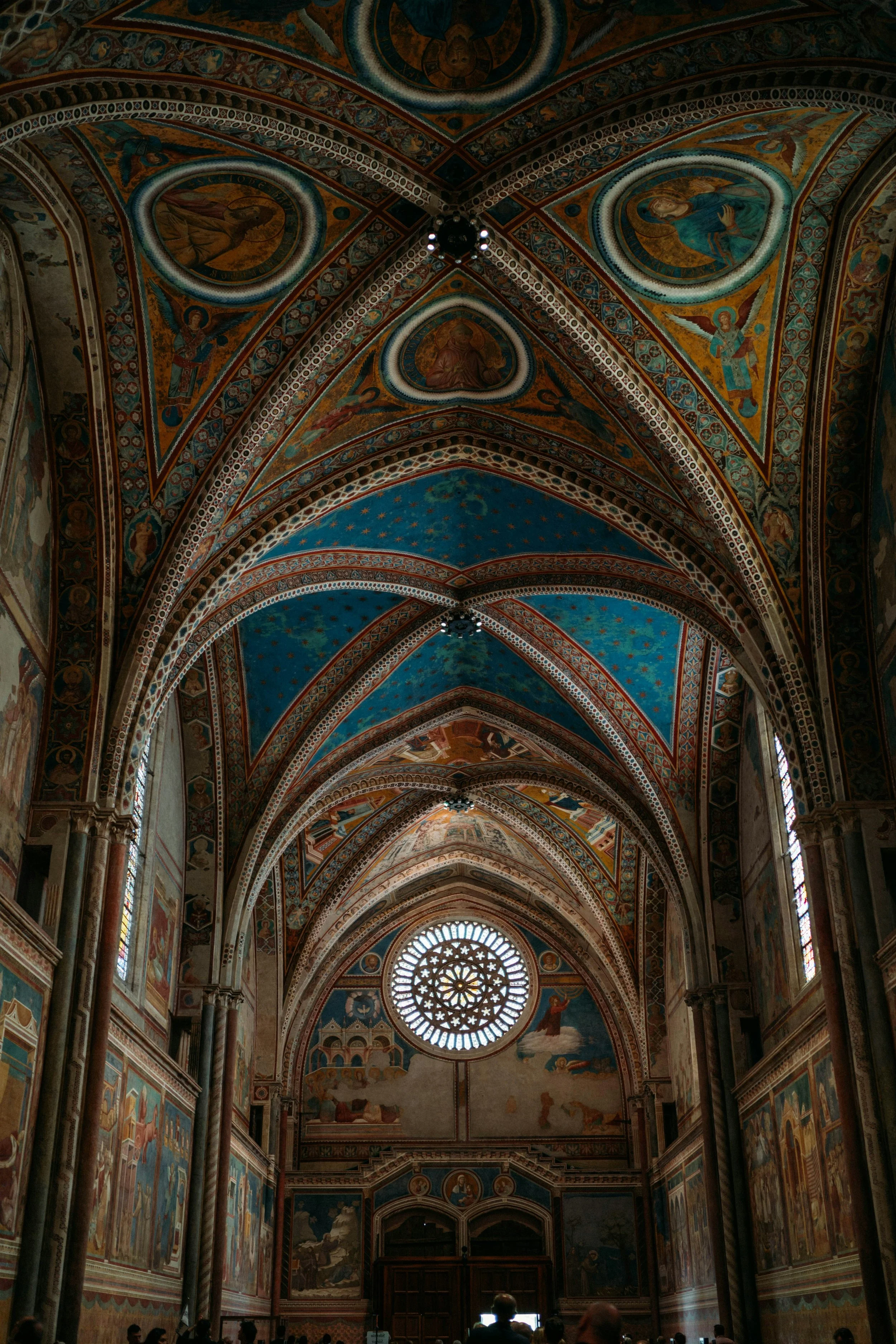 Interior view of a church with ornate painted ceilings, stained glass windows, and a large circular window.