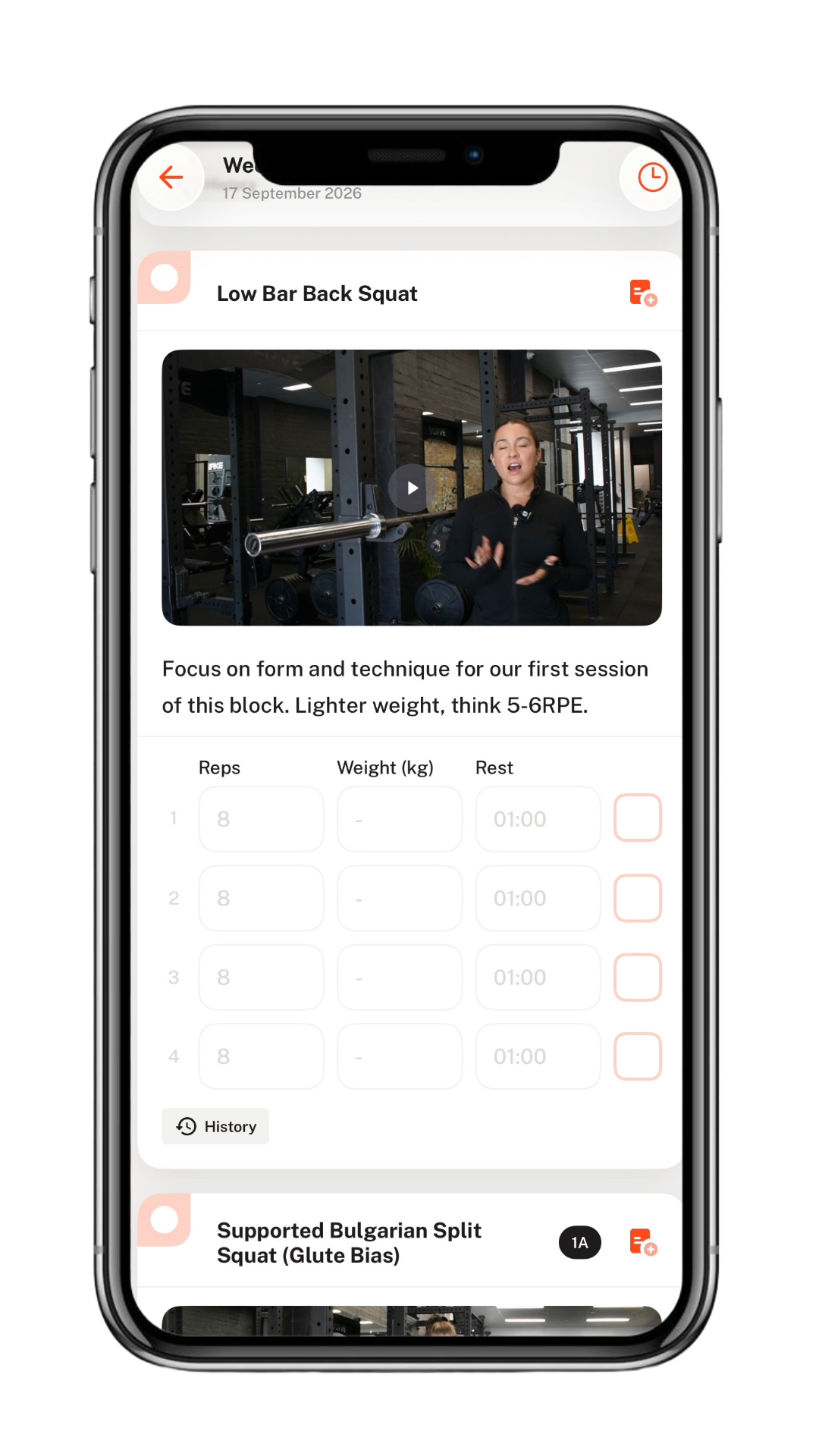 A smartphone screen showing a fitness app with a workout titled 'Low Bar Back Squat'. The app features a video of a woman explaining the exercise in a gym with weightlifting equipment. There are workout instructions, including repetitions, weight, and rest time, with a section for logging sets.