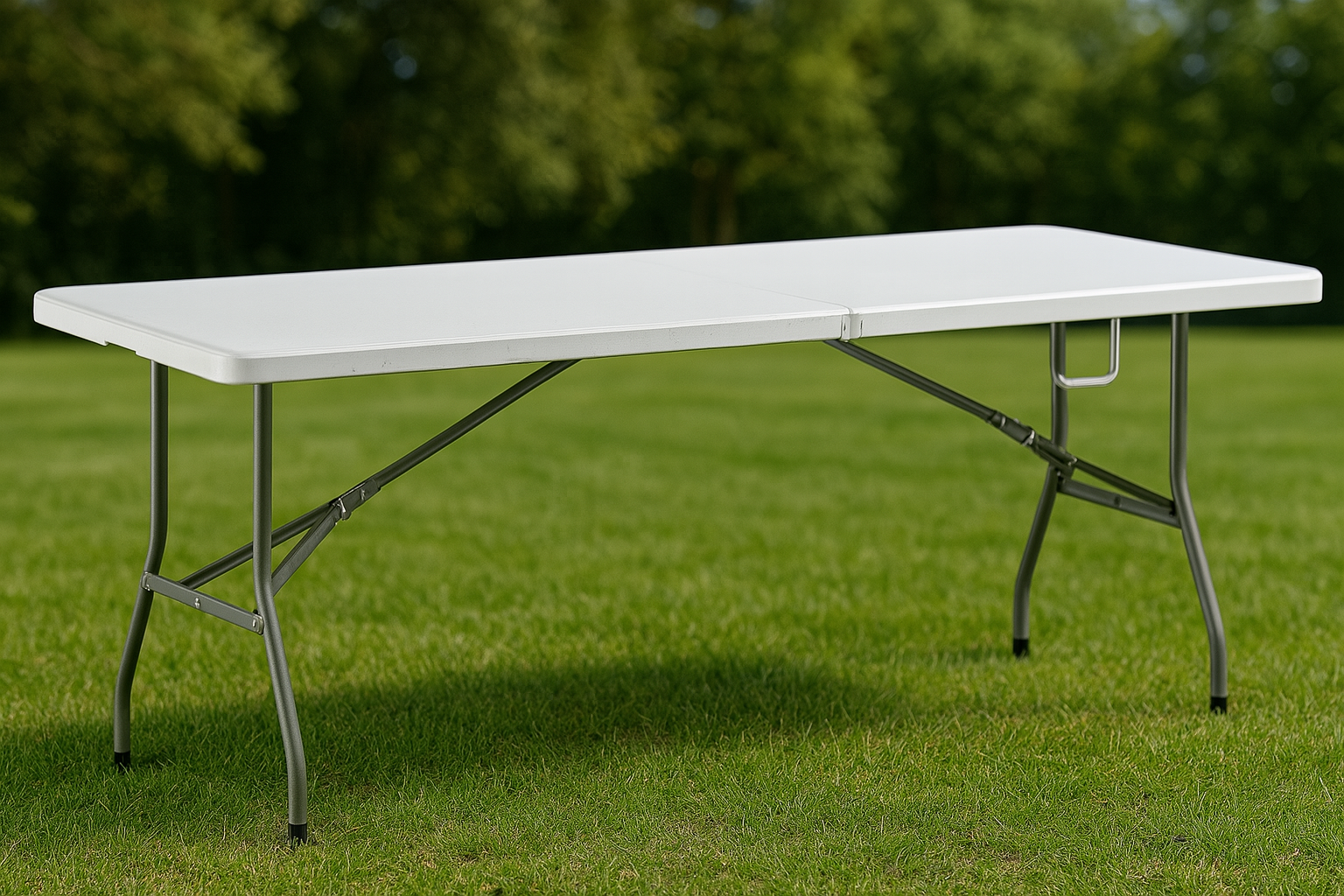 White folding table on grass with a blurred green trees background