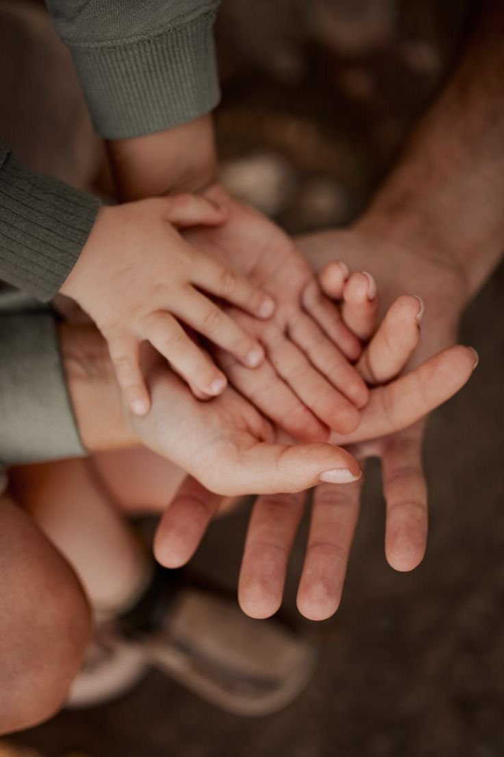 Multiple hands of different sizes stacking together, symbolizing unity or family.