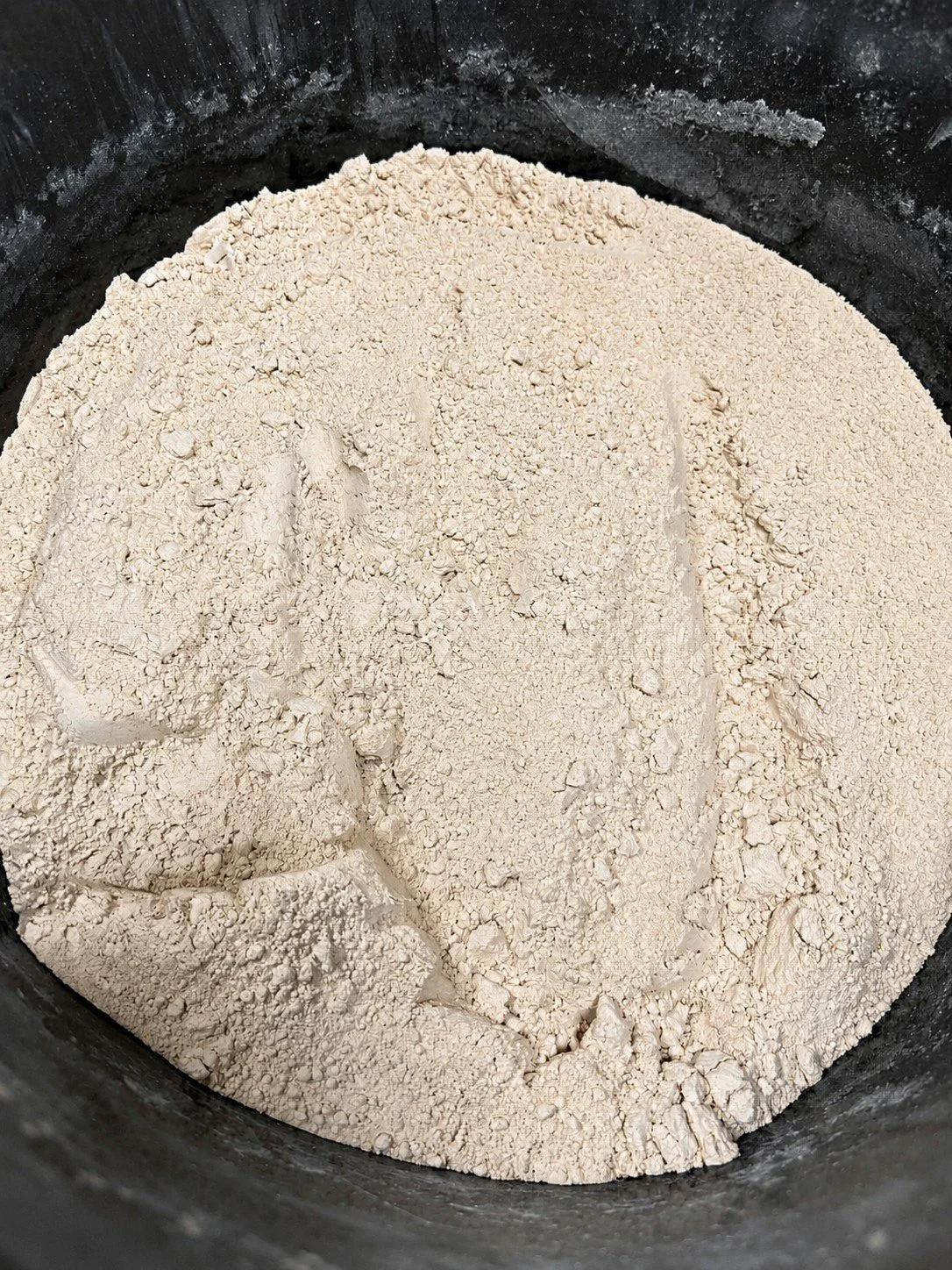 Close-up of beige powder, possibly flour or a dry ingredient, inside a black container.