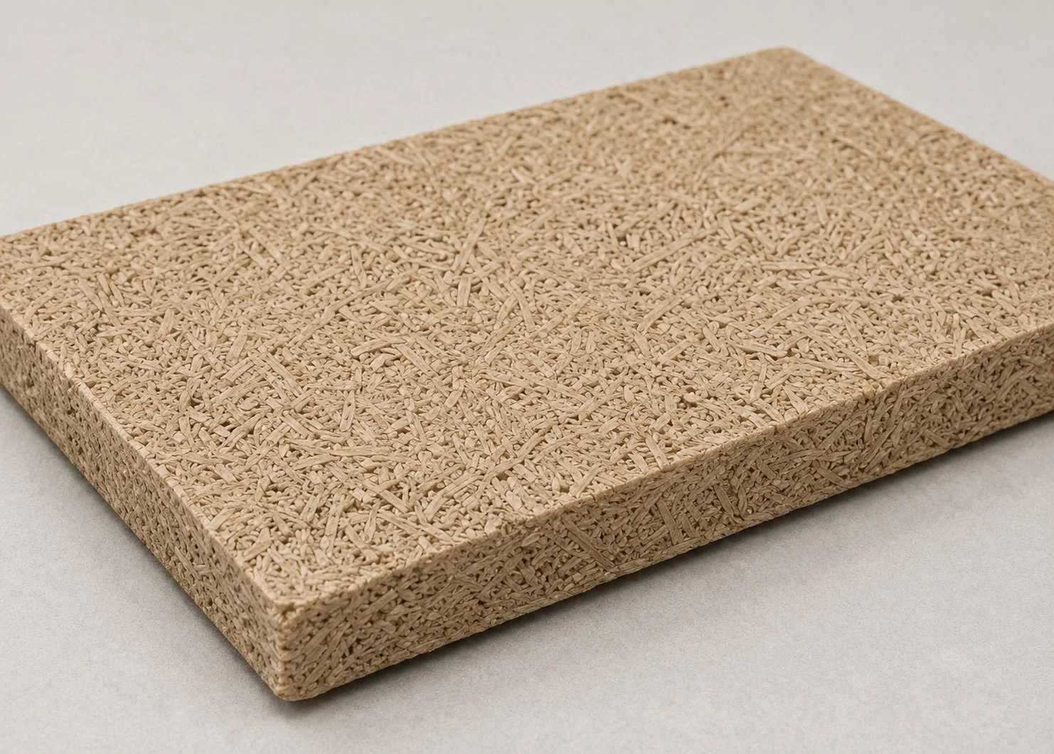A rectangular, textured beige cork board placed on a light gray surface.