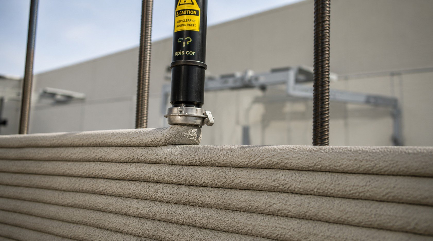 Close-up of a piece of equipment with beige layered material and black pipes, including a yellow caution label.