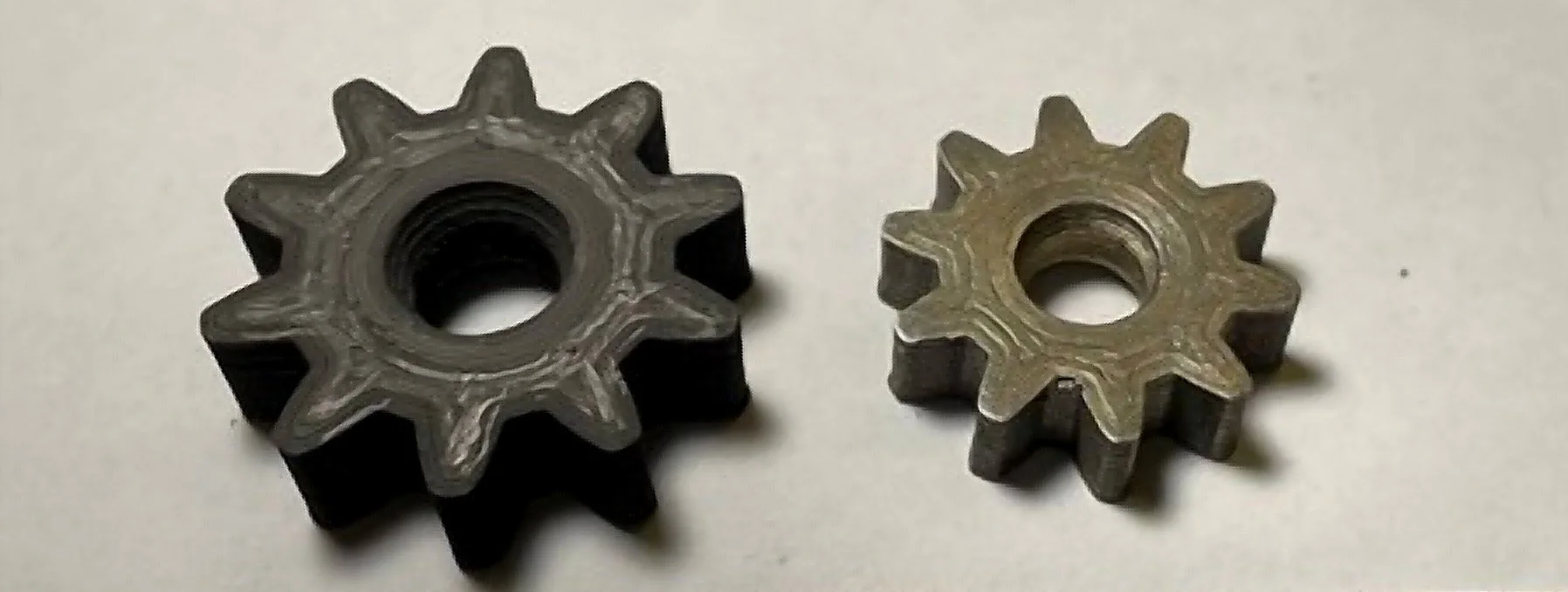 Two small metal gears with angled teeth and central holes, lying on a flat surface.