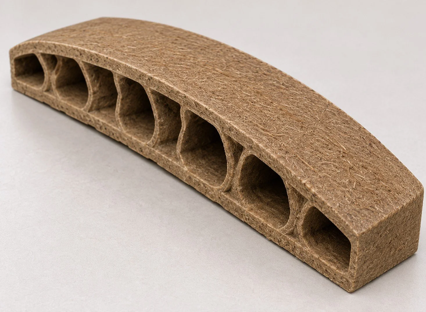 A curved, rectangular piece of finished particle board or MDF with multiple oval cutouts.
