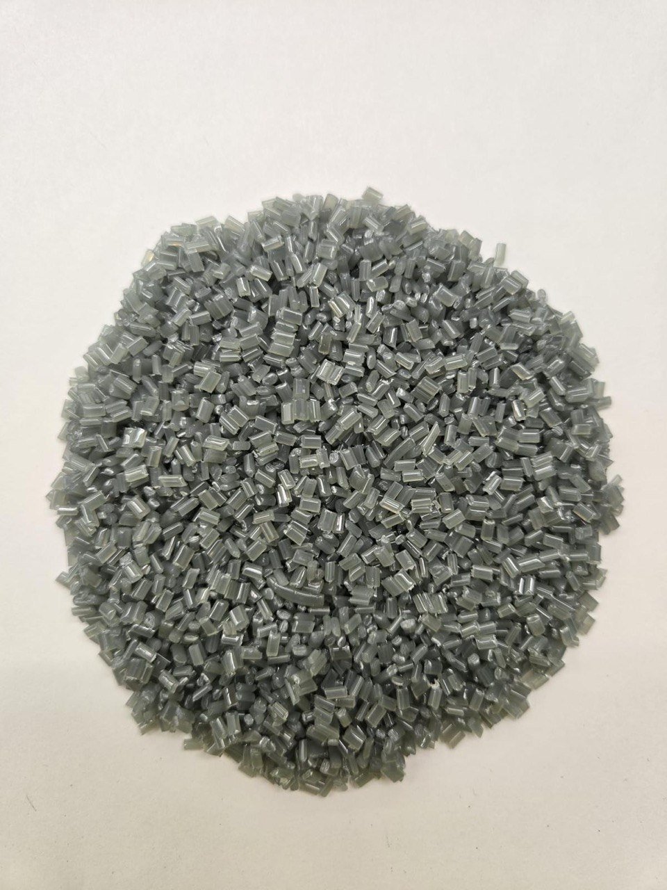 A pile of small, gray plastic pellets on a white background.