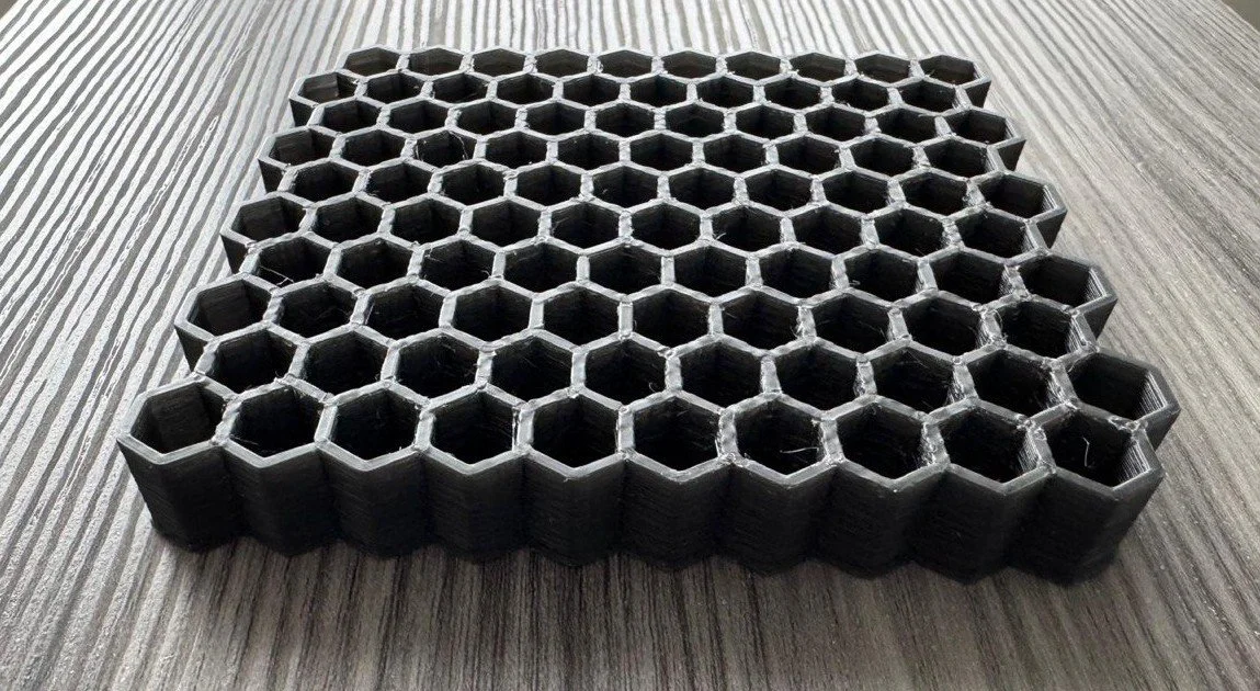 3D-printed black honeycomb-shaped object on a wooden surface.