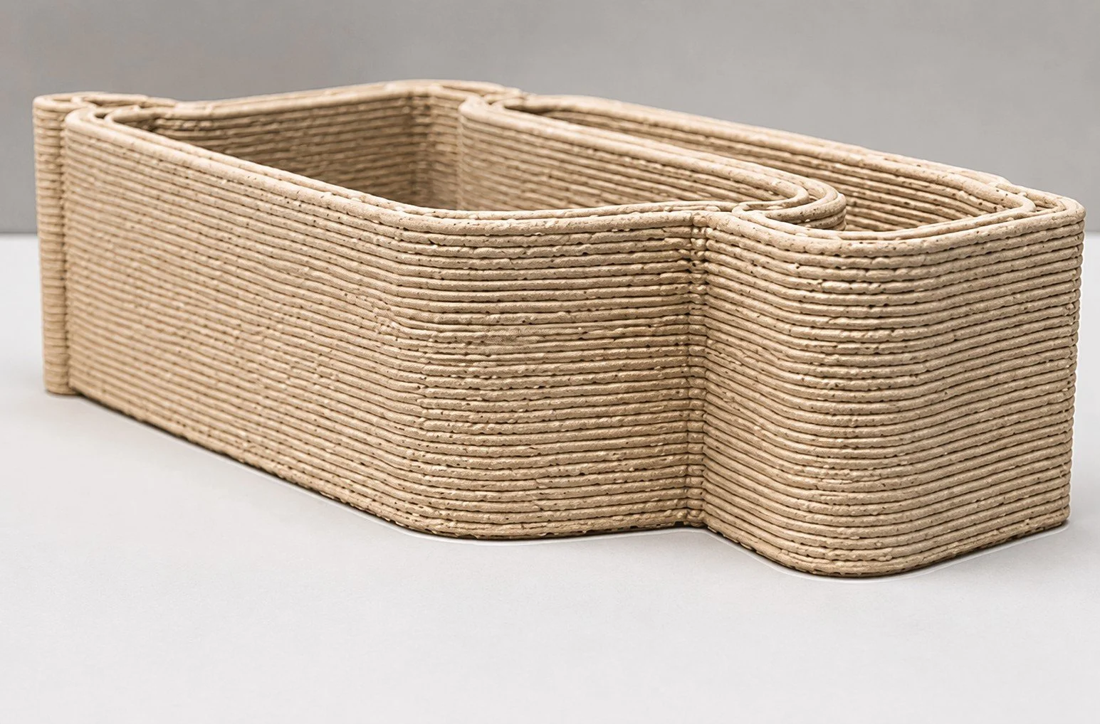 A rectangular woven basket made of natural-colored material, placed on a white surface with a plain background.