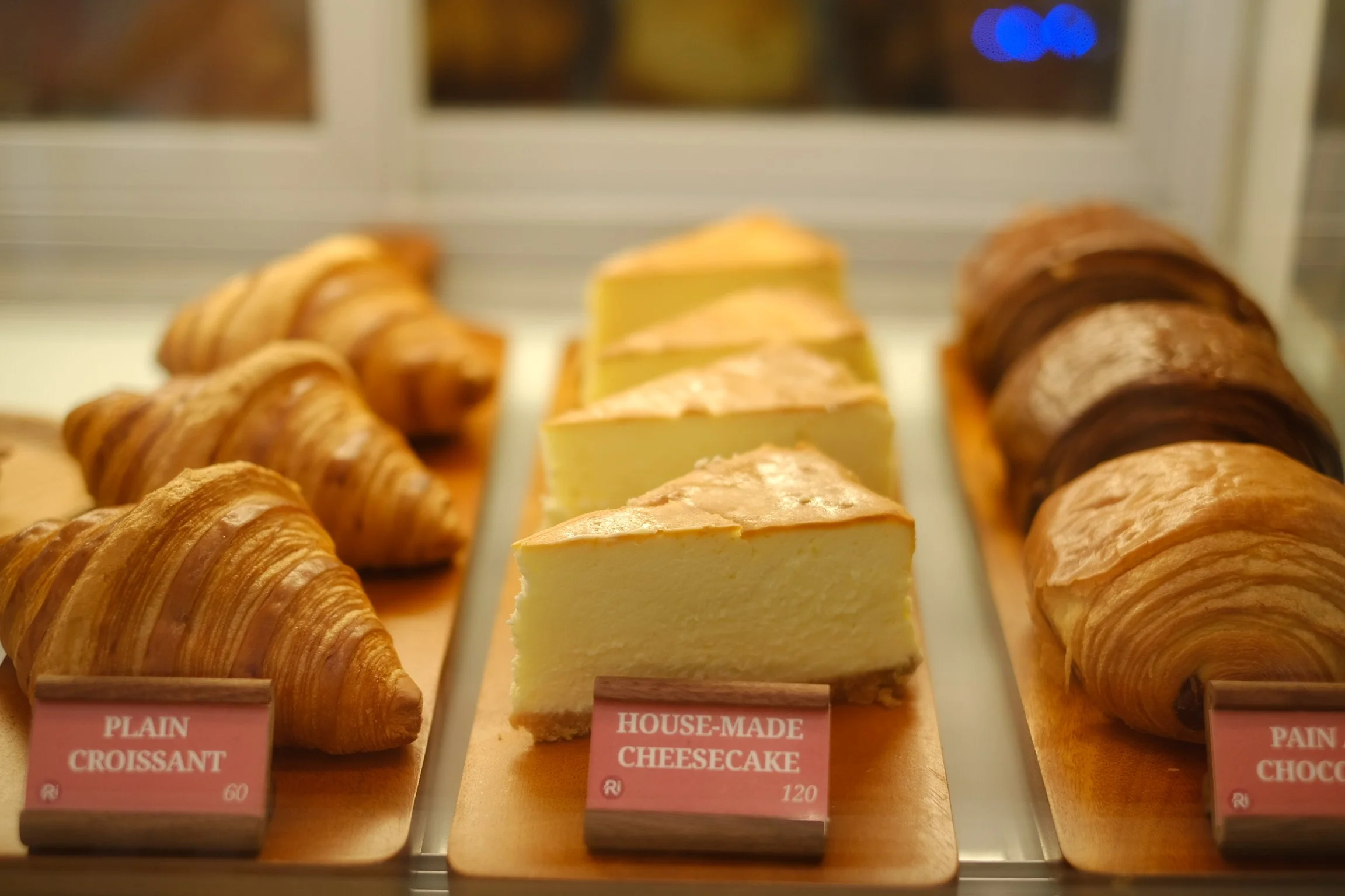 Display of assorted baked goods including croissants and cheesecake slices at a bakery