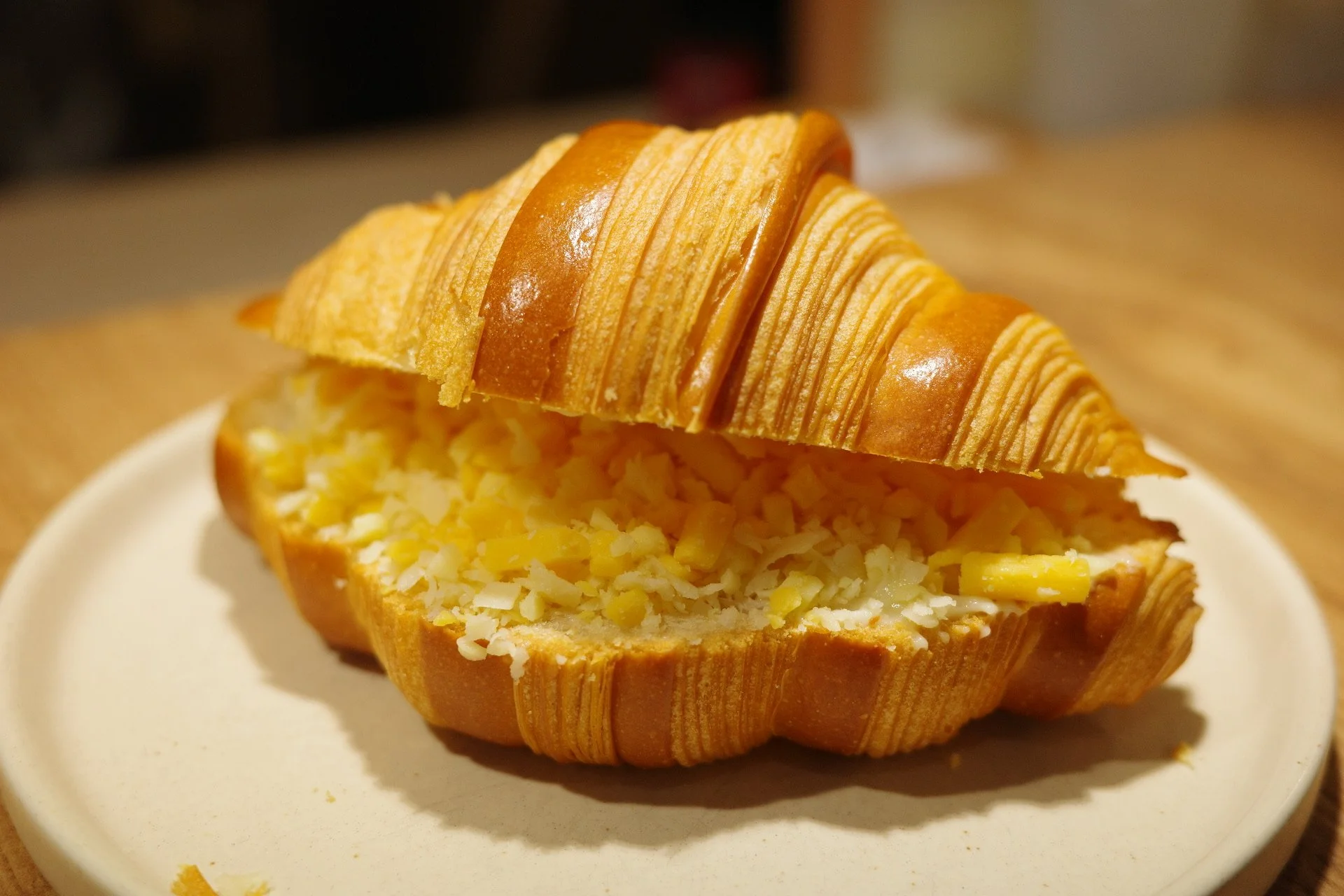 A bowl of bread filled with yellow shredded cheese, with the top of the bread sliced open to reveal the cheese inside.