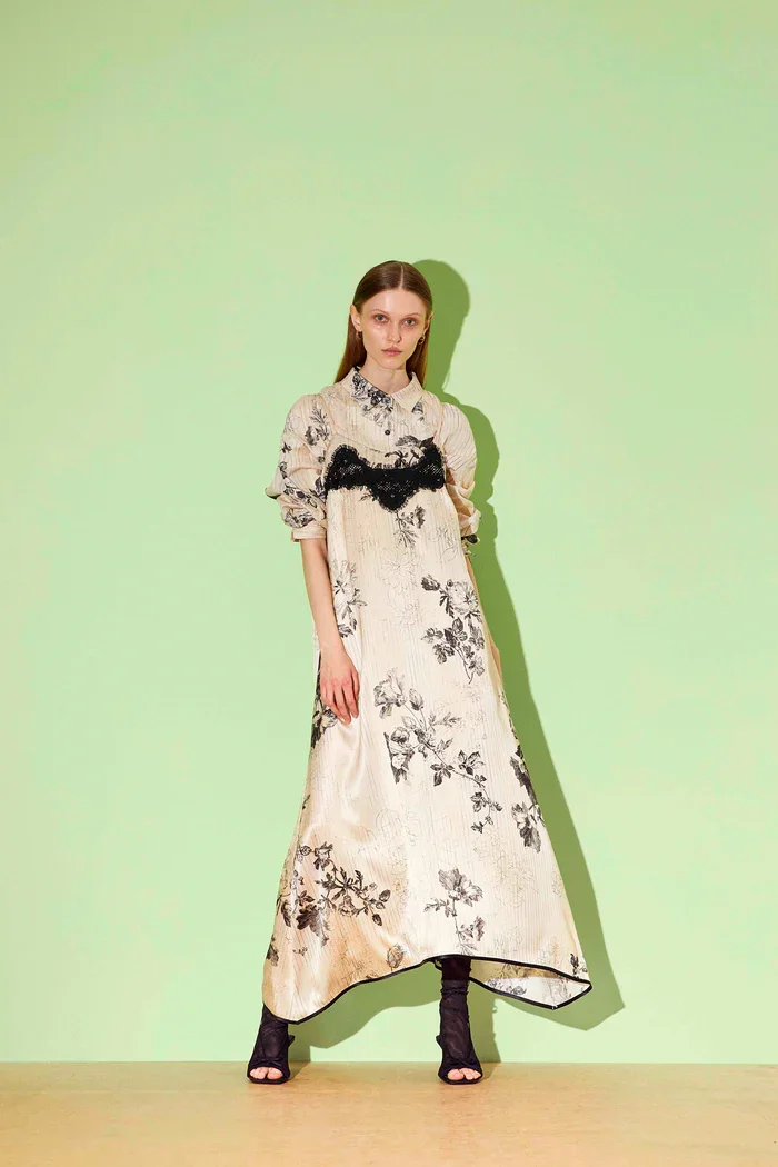 Frau in langem, floral bedrucktem Kleid mit schwarzen Schnürstiefeln vor grünem Hintergrund