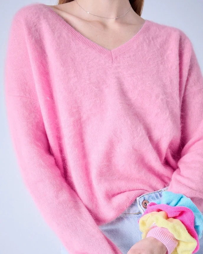 Person trägt einen pinken Pullover und hält bunte Mädchenarmbänder aus Stoff.