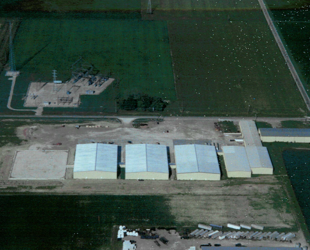 An overhead image featuring multiple warehouse buildings surrounded by green farmland