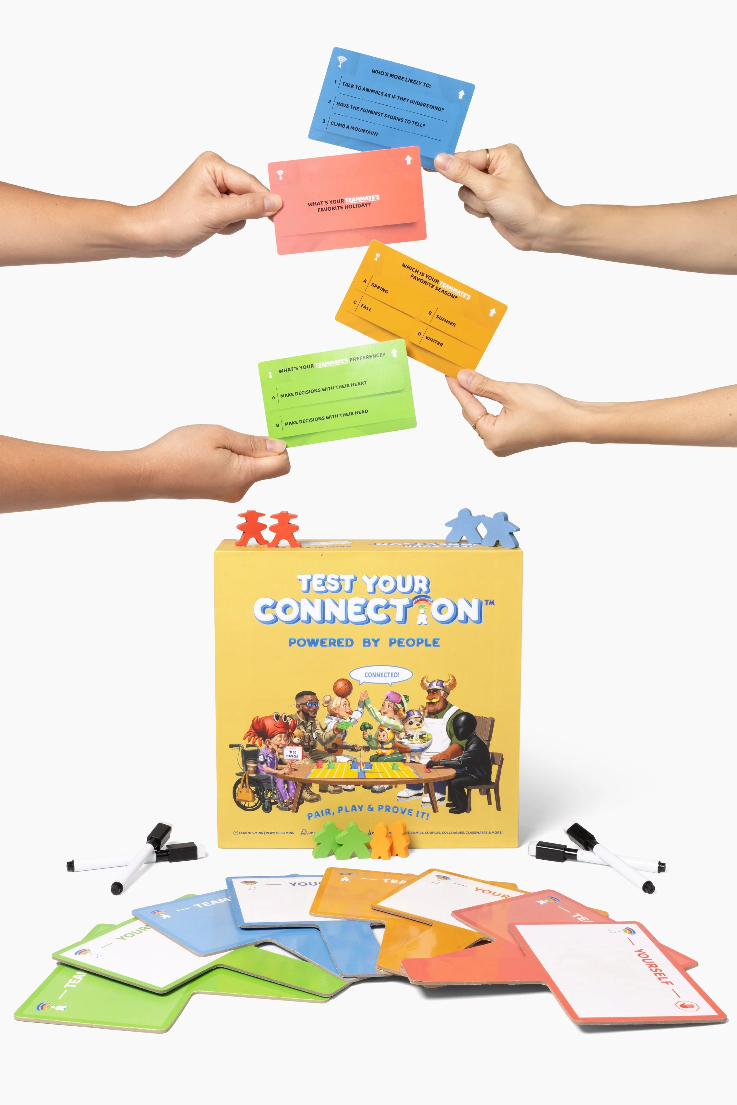 The image shows a colorful card game called 'Test Your Connection'. Several playing cards with different colors and prompts are scattered on the table, with four hands holding some of these cards. The game box features diverse cartoon characters around a table, emphasizing themes of pairing, playing, and proving connections.
