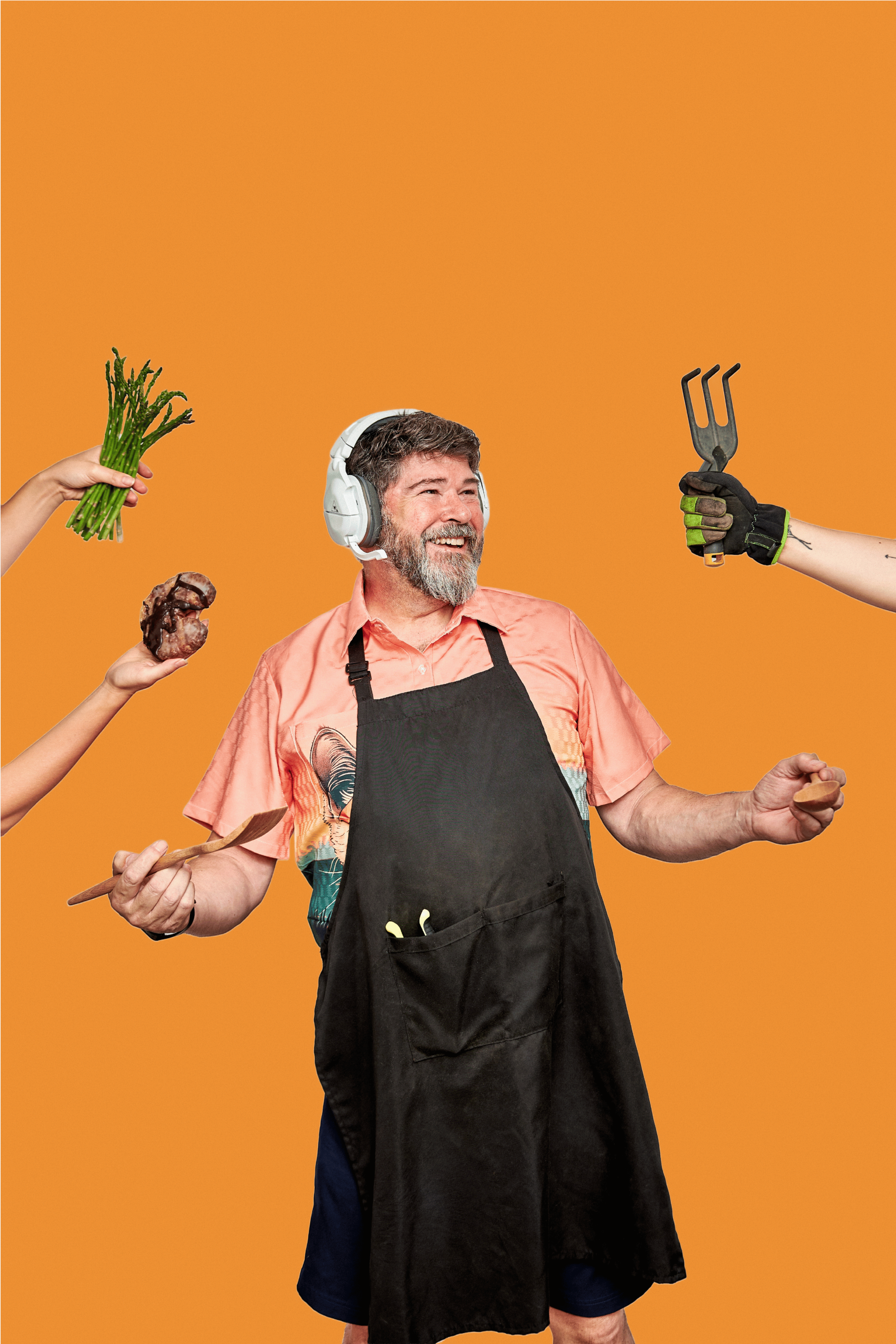 Smiling man wearing headphones and an apron, with various hands offering food items against a bright orange background.