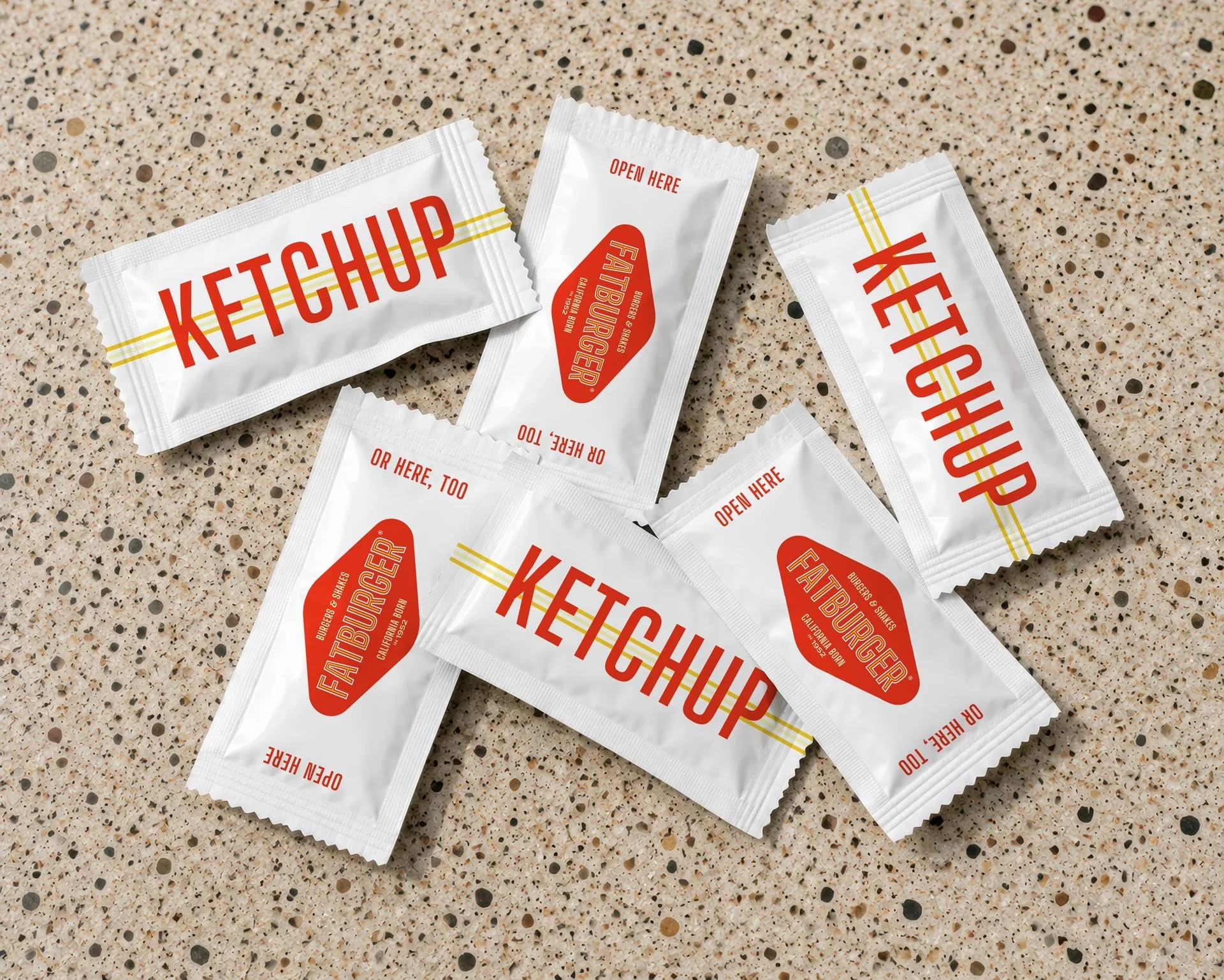 Overhead shot of disposable ketchup packets designed for FATBURGER rebranding
