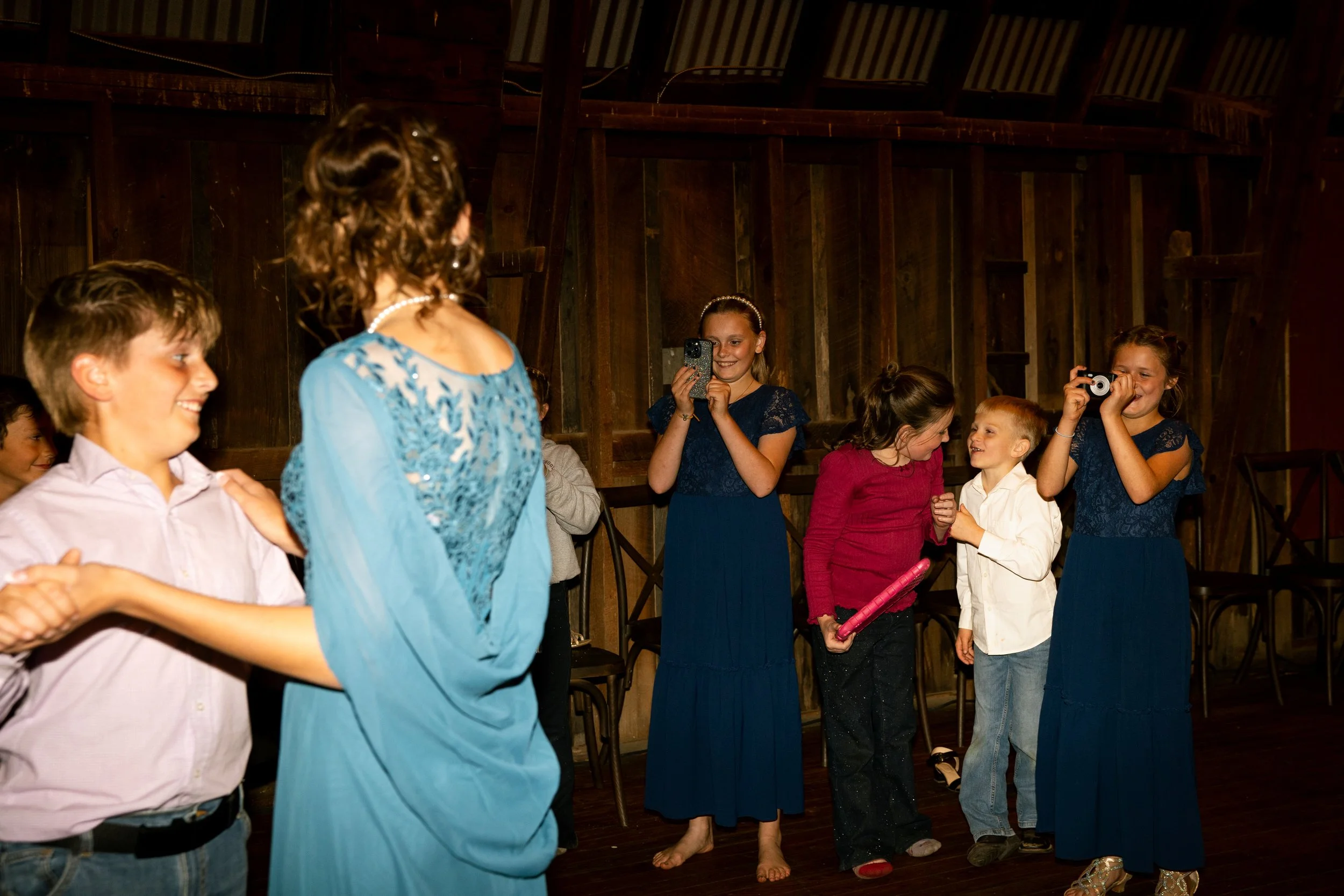 Group of children and a woman at a birthday party, some children taking photos and interacting.