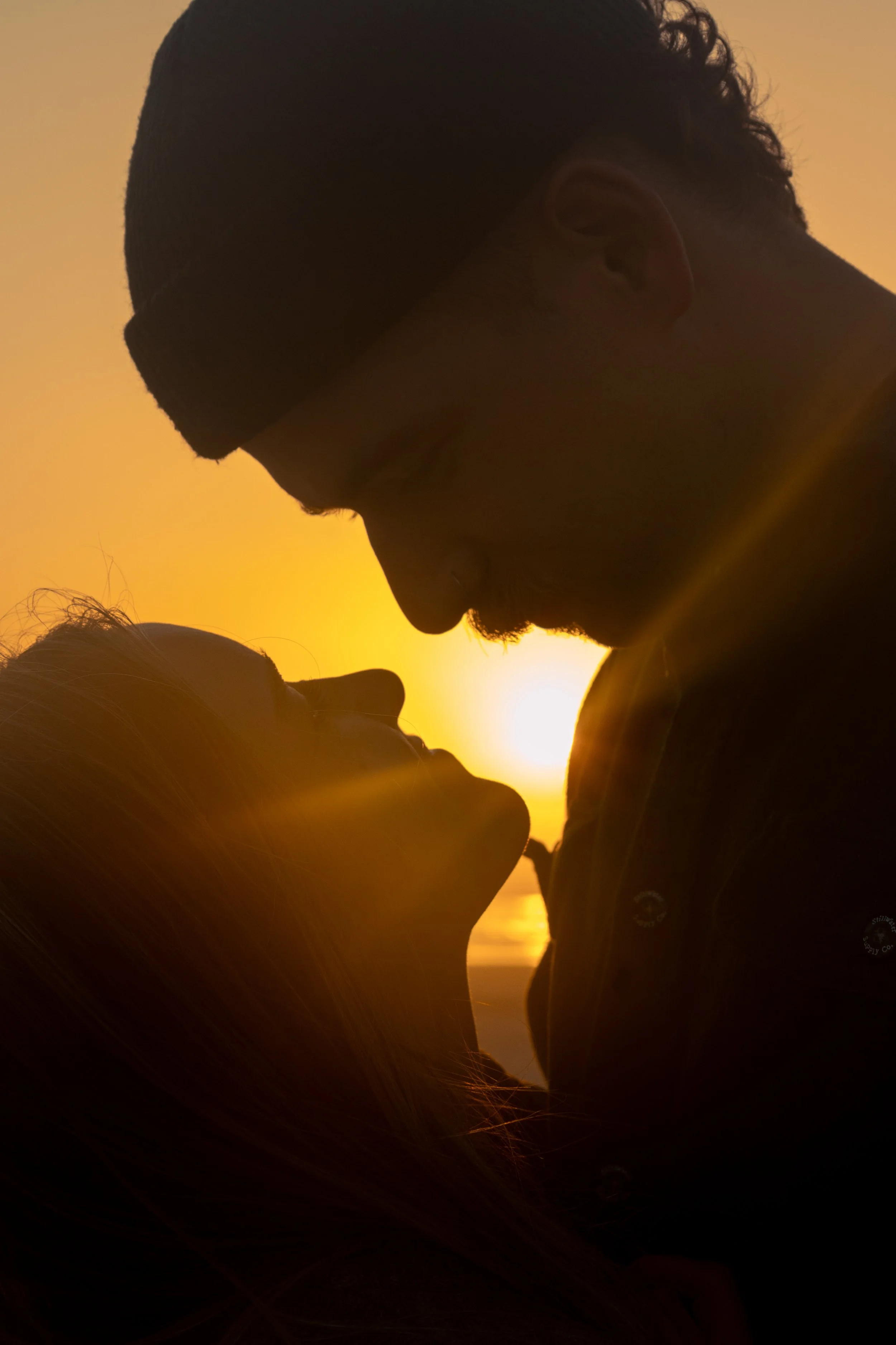 Silhouette of a couple about to kiss during sunset.