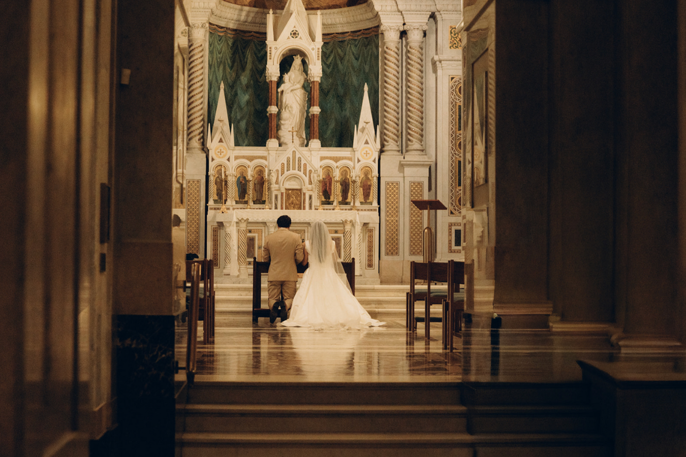A bride and groom kneeling at the altar inside a church during their wedding ceremony.