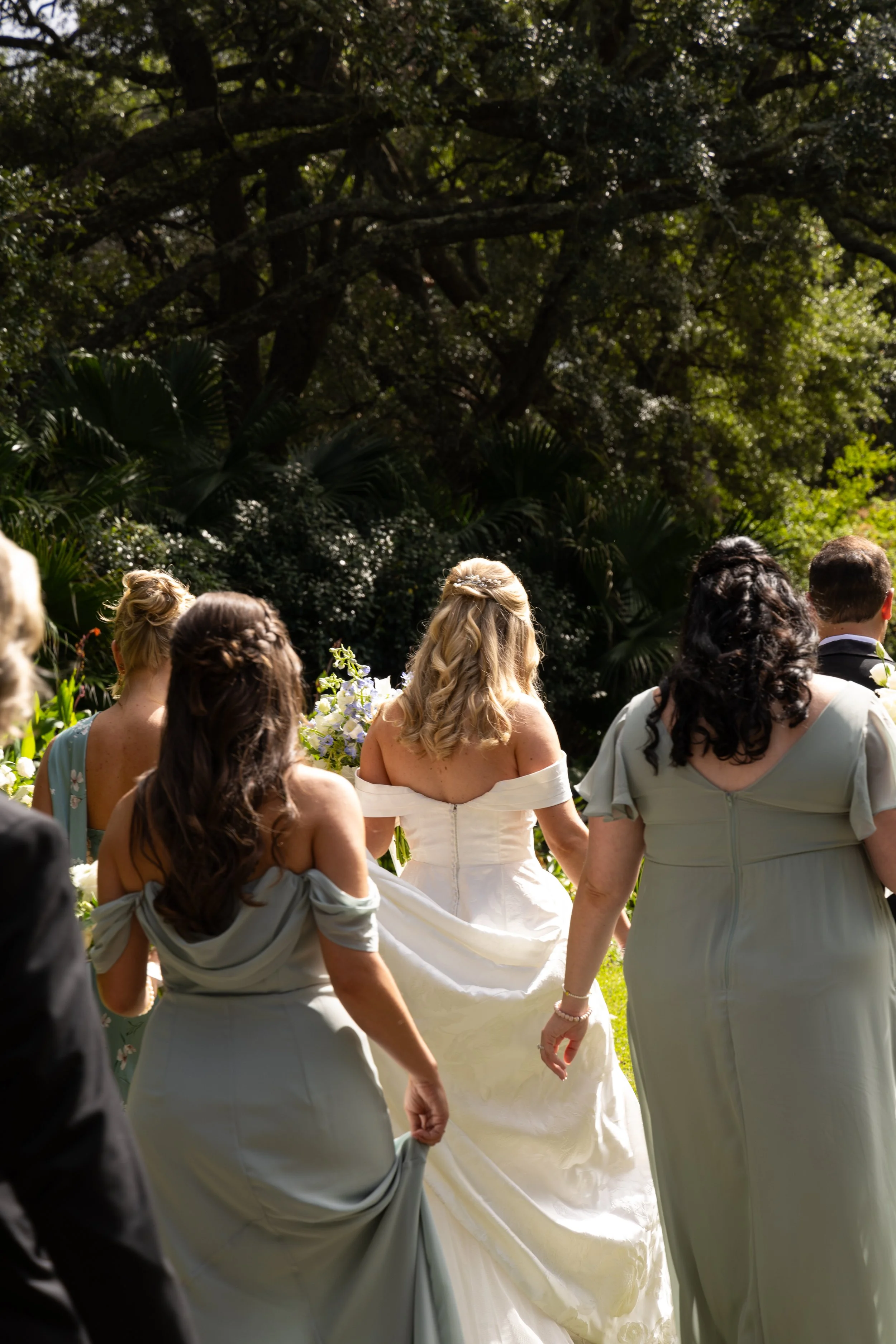 A group of women and men at a wedding ceremony outdoors, with trees and greenery in the background. Shot at Hampton Park in Charleston, South Carolina.