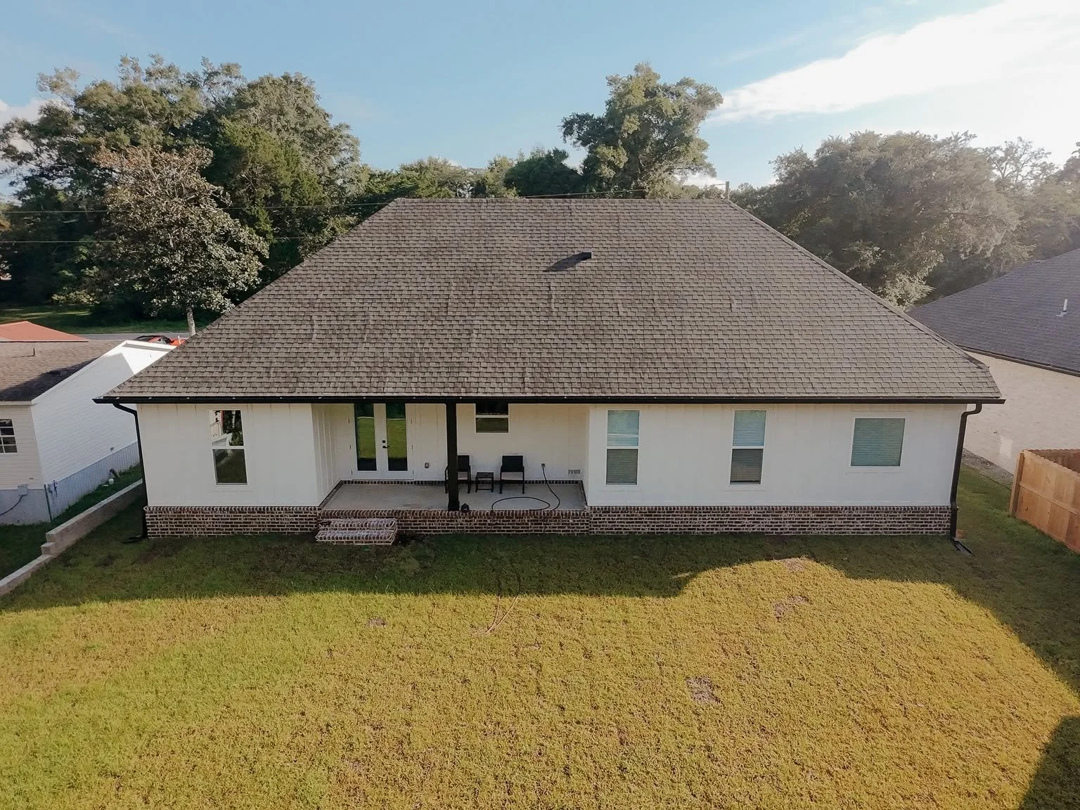 Rear view of a newly built custom home in Pace, Northwest Florida, featuring a covered back porch, spacious backyard, and a practical layout designed for comfortable family living and outdoor enjoyment
