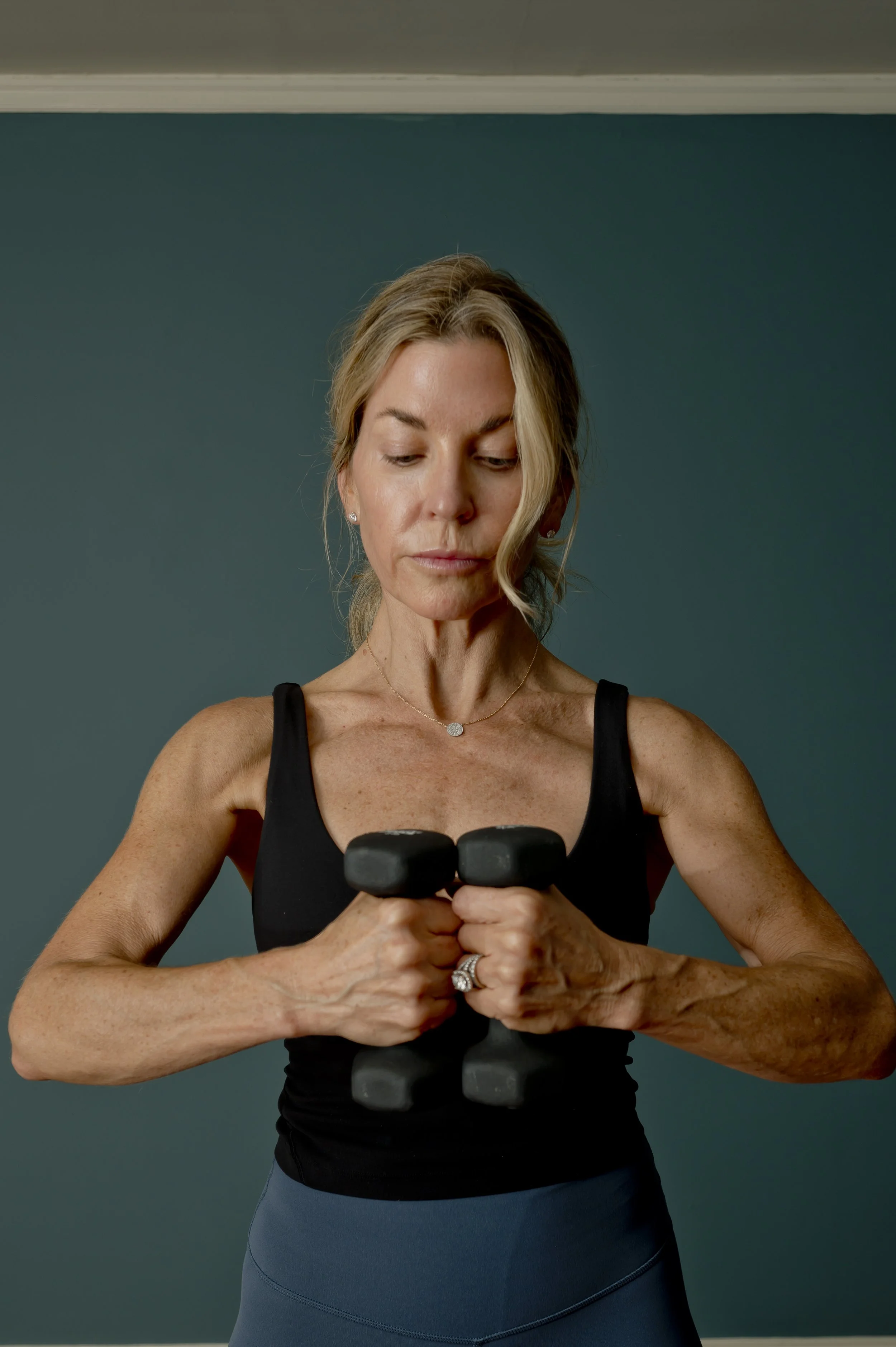 A woman instructor lifting light weights in front of her body, symbolizing energy and wellness.