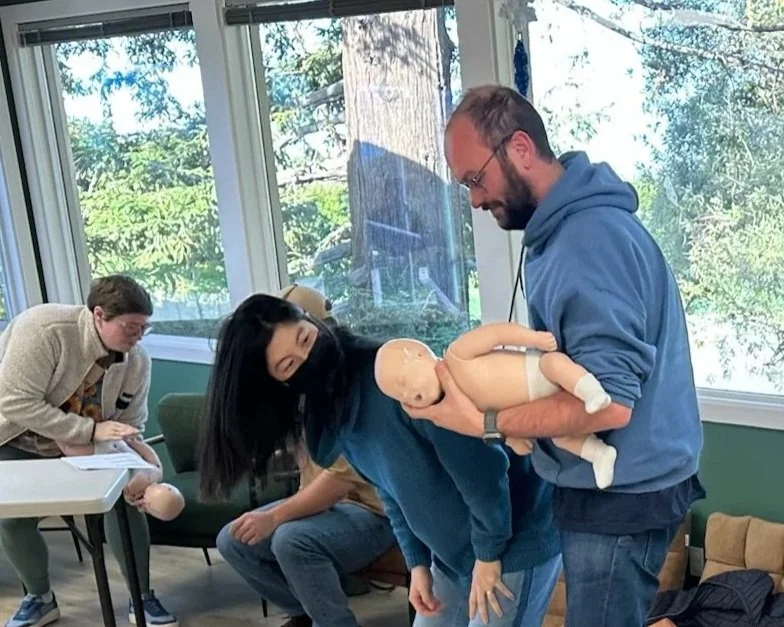 Parent practicing infant CPR on a manikin during a hands-on preparedness class at Adrouny Village Wellness in San Jose