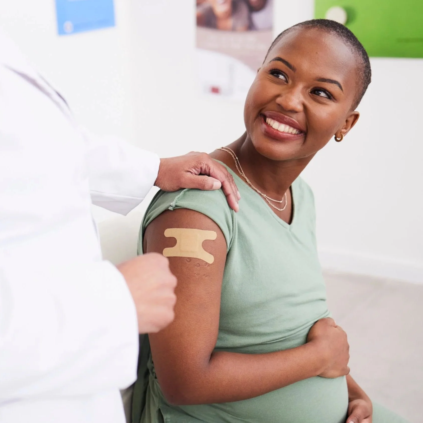 Pregnant woman smiling with a bandage on her arm after receiving an RSV vaccination