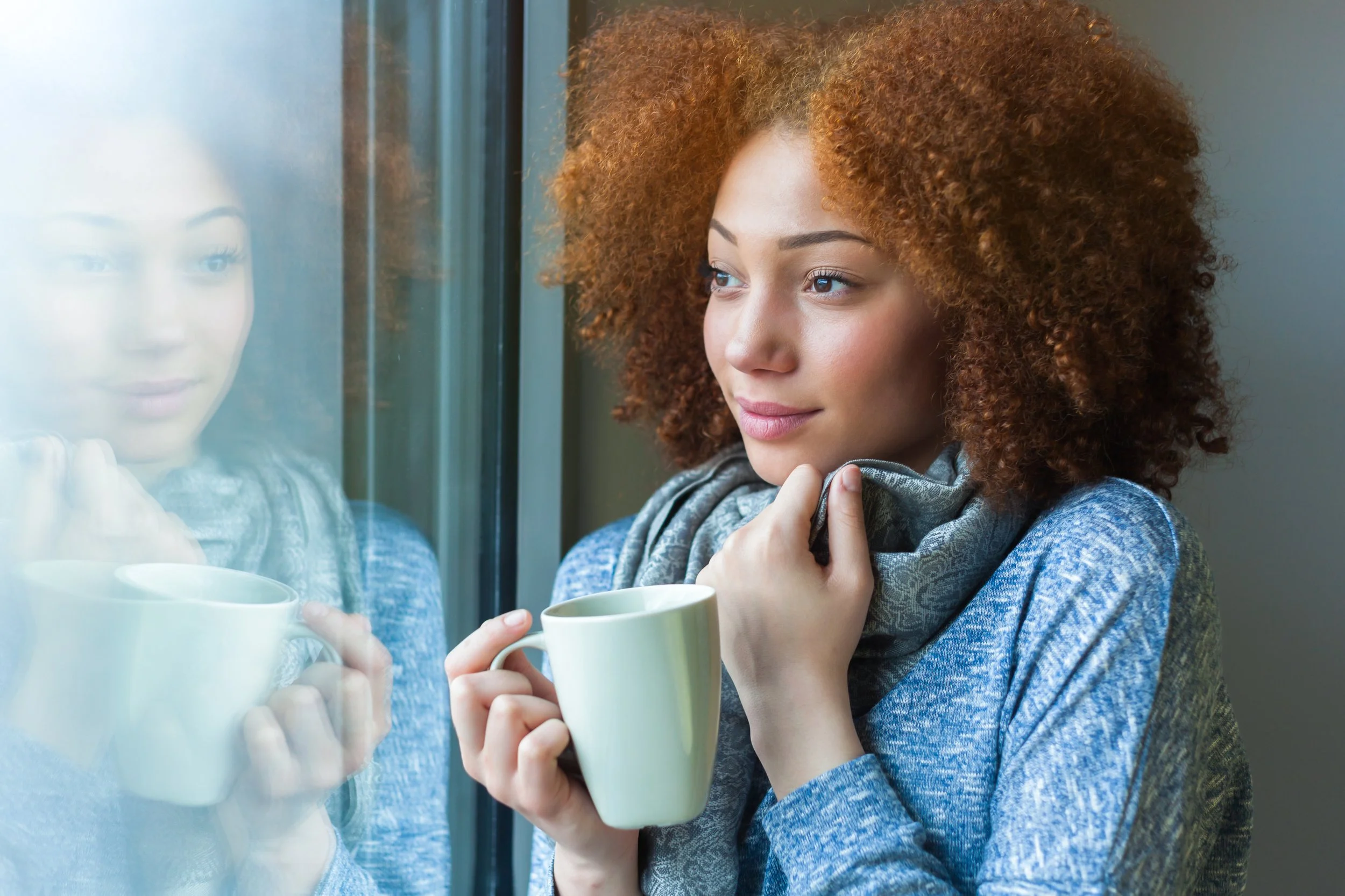 Woman sitting by a window drinking tea after receiving Immune Boost IV therapy